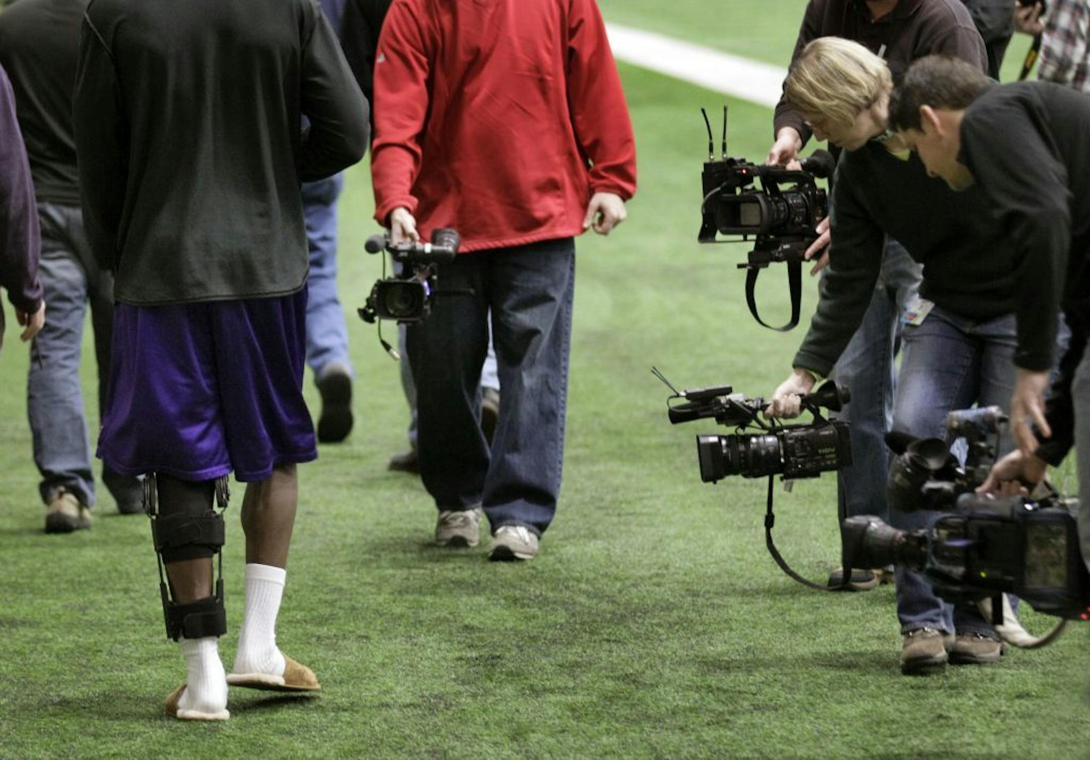 Under the close coverage of the local media, Adrian Peterson walks back to the lockeroom after a Press Conference with trainer Eric Sugarman to talk about Peterson's knee surgery and projected recovery.