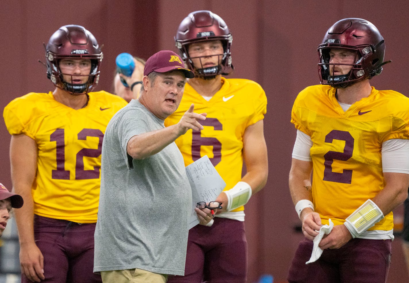 Gophers football offensive coordinator Kirk Ciarrocca speaks with quarterbacks Cole Kramer (12), Jacob Knuth (6) and Tanner Morgan (2) during the football team's open practice Saturday, August 6, 2022 at Athletes Village on the campus of the University of Minnesota in Minneapolis. ]