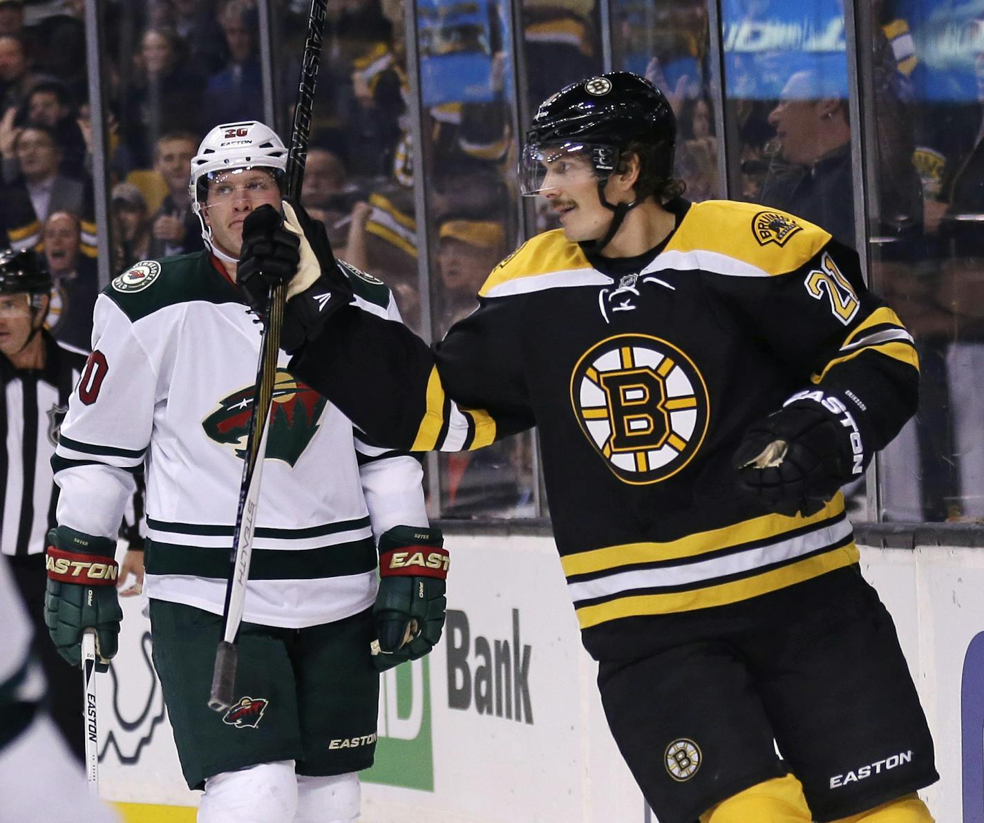 Boston Bruins left wing Loui Eriksson, right, skates past Minnesota Wild defenseman Ryan Suter, center, after scoring his first goal of the game during the second period of an NHL hockey game in Boston Thursday, Nov. 19, 2015. Eriksson had a hat trick in the game. (AP Photo/Charles Krupa)