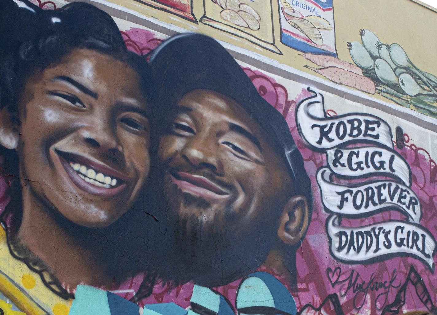 Kimberly Arellano and Abigail Tendrio pause in front of a mural put up of Kobe Bryant and his daughter along Pickford Street in Los Angeles, Monday, Jan. 27, 2020. Bryant, the 18-time NBA All-Star who won five championships and became one of the greatest basketball players of his generation during a 20-year career with the Los Angeles Lakers, died in a helicopter crash Sunday. (David Crane/The Orange County Register via AP)