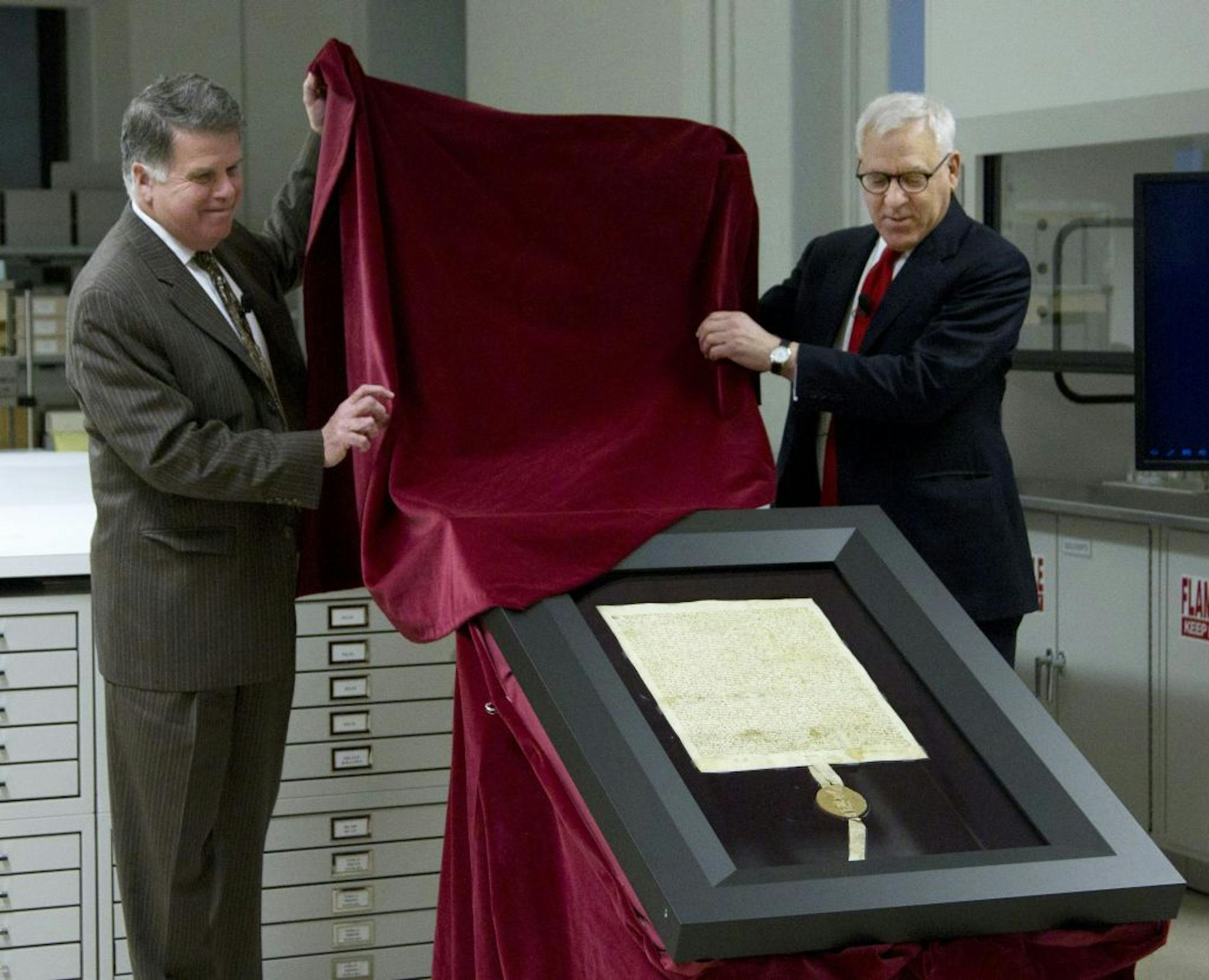 Carlyle Group co-founder and Magna Carta owner David Rubenstein, right, and Archivist of the U.S. David Ferriero, unveil the 1297 Magna Carta in its new state-of-the-art encasement at the National Archives in Washington, Thursday, Feb. 2, 2011.