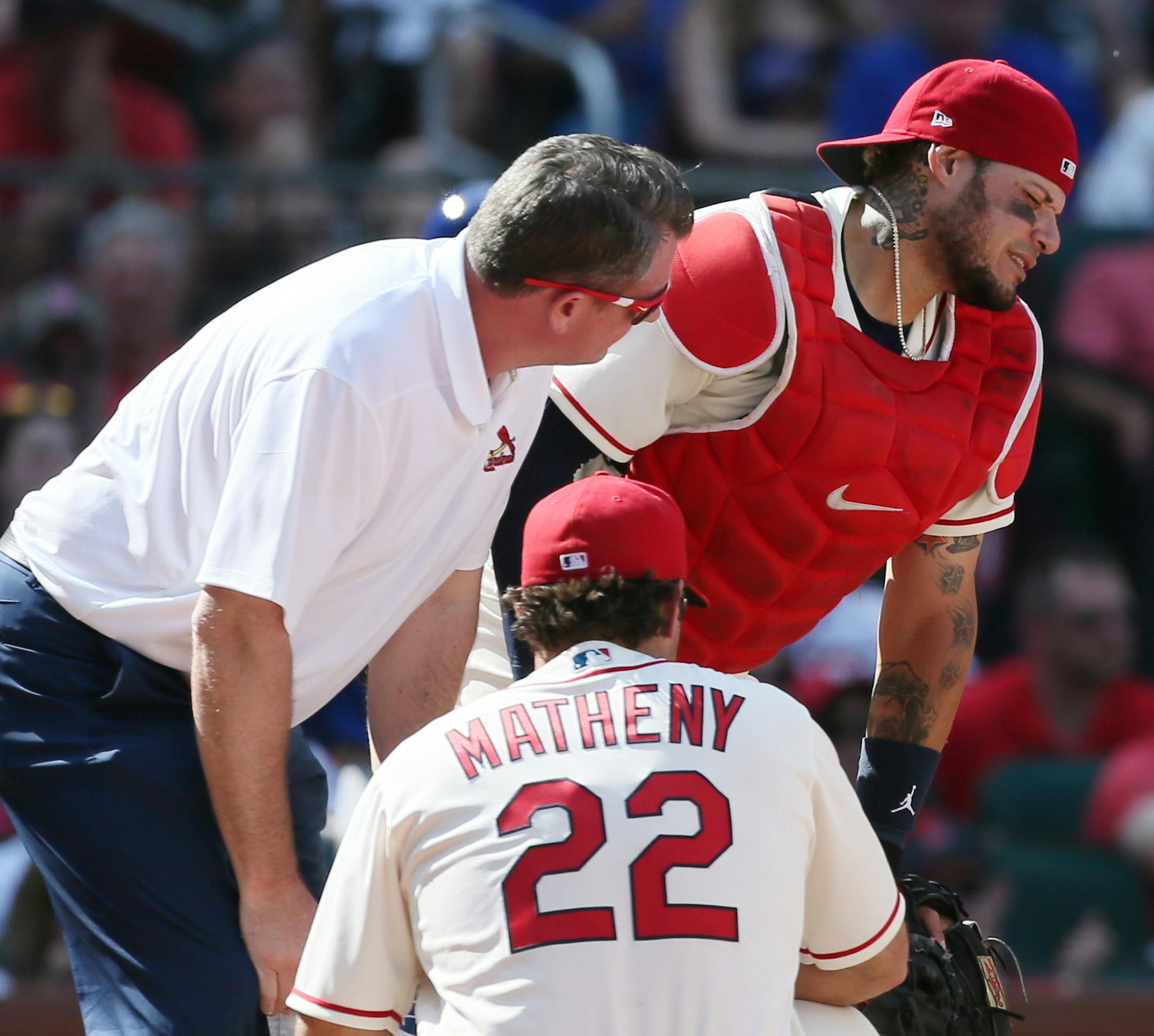 St. Louis Cardinals catcher Yadier Molina is tended to by assistant athletic trainer Chris Conroy and manager Mike Matheny (22) after he was struck by a ball while catching in the ninth inning against the Chicago Cubs at Busch Stadium in St. Louis on Saturday, May 5, 2018. The Cards won, 8-6, in 10 innings. (Chris Lee/St. Louis Post-Dispatch/TNS)