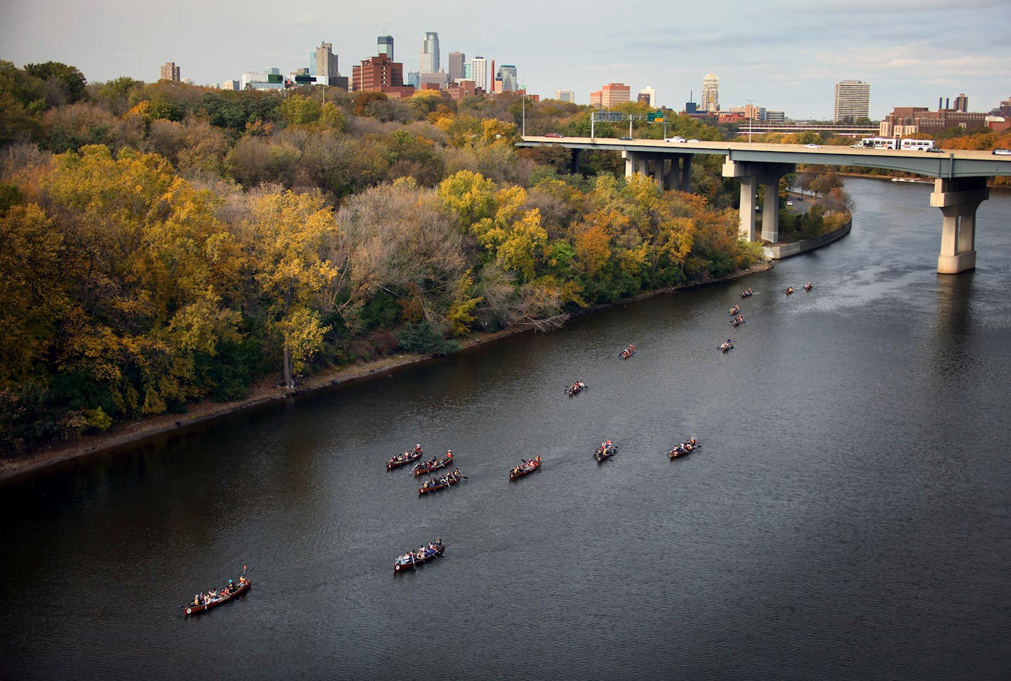 Below the buzz of the Franklyn Avenue bridge and in the shadow of downtown Minneapolis, a flotilla of large voyager canoes full of students paddle down the Mississippi River.