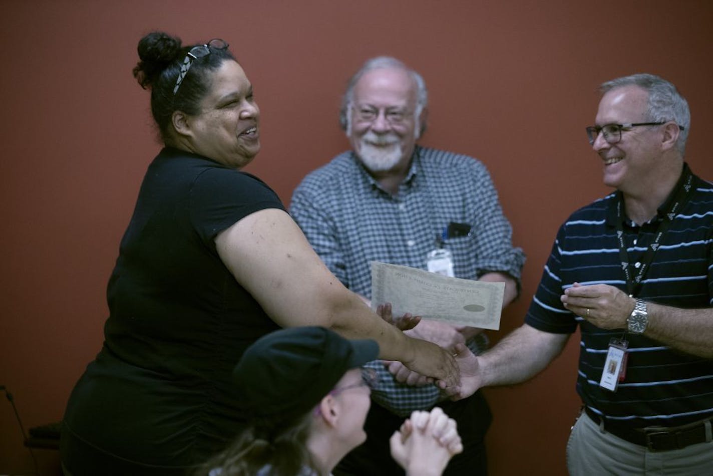 Cynthia Child left, received her certificate from instructor Niels Andersen right, as Eric Hughbanks looks on during graduation ceremonies at Avivo. She said the Legislature's investment in programs like hers is money well spent, employing people who might otherwise tax the social safety net.