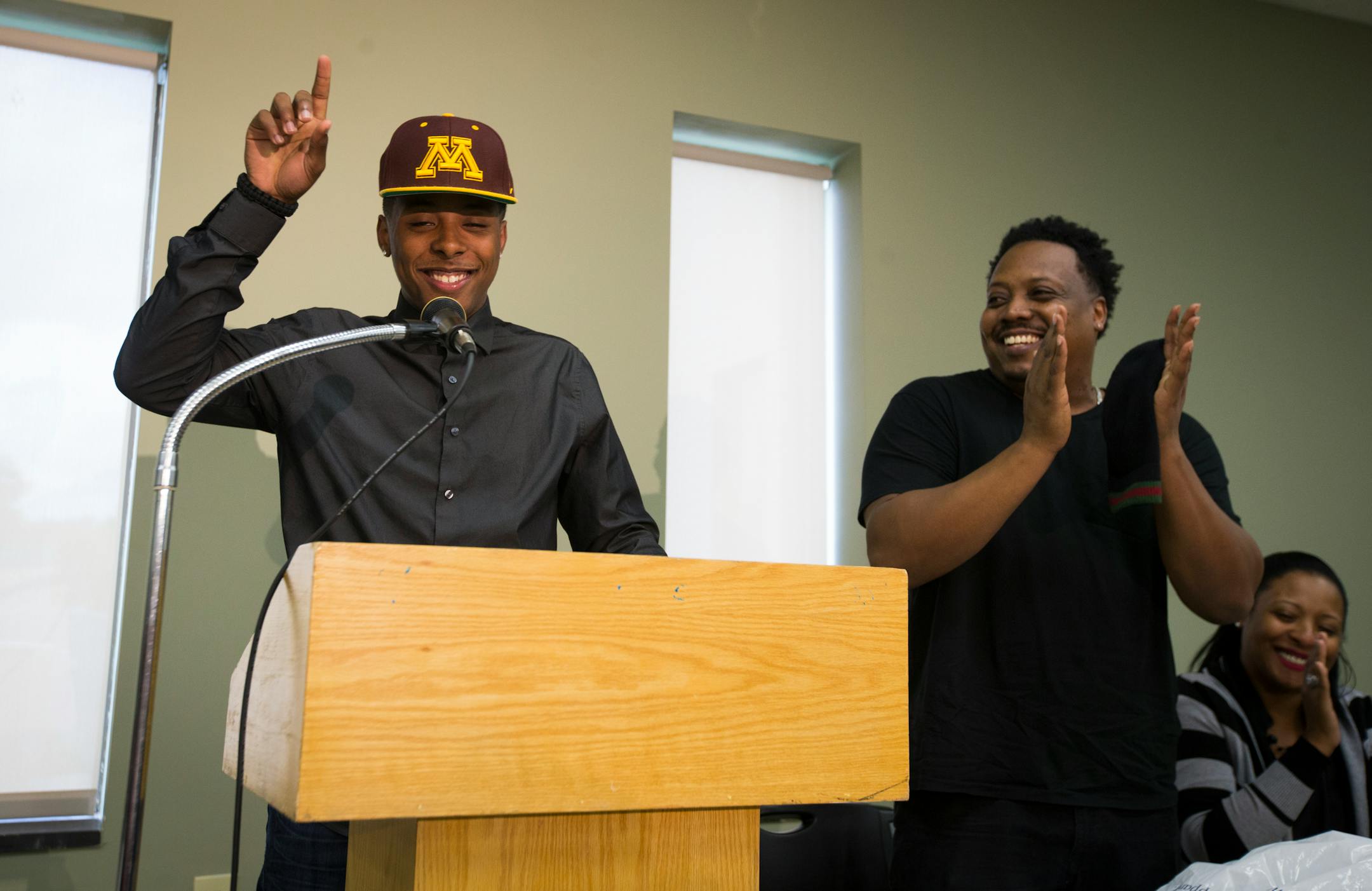 Jarvis Johnson, DeLaSalle basketball star, put on a Gophers hat as announced his college choice at DeLaSalle High School on Friday, Sept. 12, 2014, in Minneapolis. At right is his father Curtis Johnson.