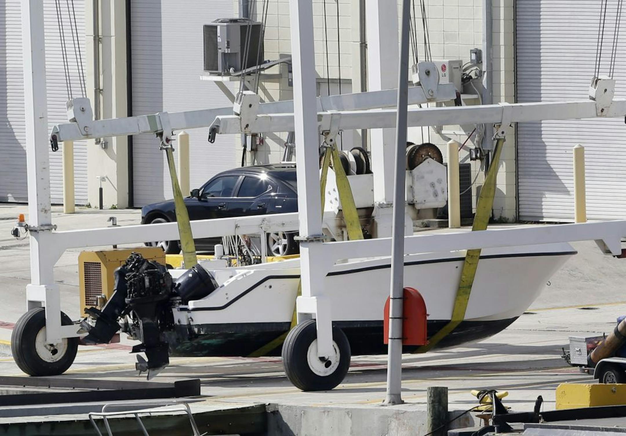 A small white boat with its center console missing sits on the dock after authorities lifted it out of the water, Wednesday, Oct. 16, 2013 at the U.S. Coast Guard Station Miami Beach, in Miami Beach, Fla. Four women died and 10 people were taken into custody after the boat with more than a dozen people aboard, including Haitian and Jamaican nationals, capsized early Wednesday in the waters off South Florida. It was overloaded and lacked lifejackets, according to the Coast Guard.