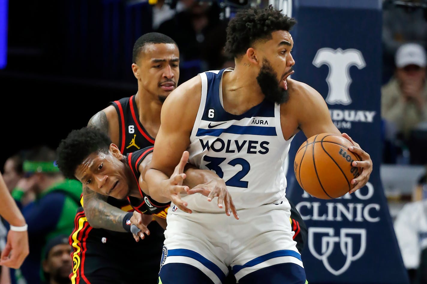 Minnesota Timberwolves center Karl-Anthony Towns, right, works to the basket as Atlanta Hawks forwards De'Andre Hunter, left, and John Collins, center, defend him in the third quarter of an NBA basketball game Wednesday, March 22, 2023, in Minneapolis. The Timberwolves won 125-124. (AP Photo/Bruce Kluckhohn)