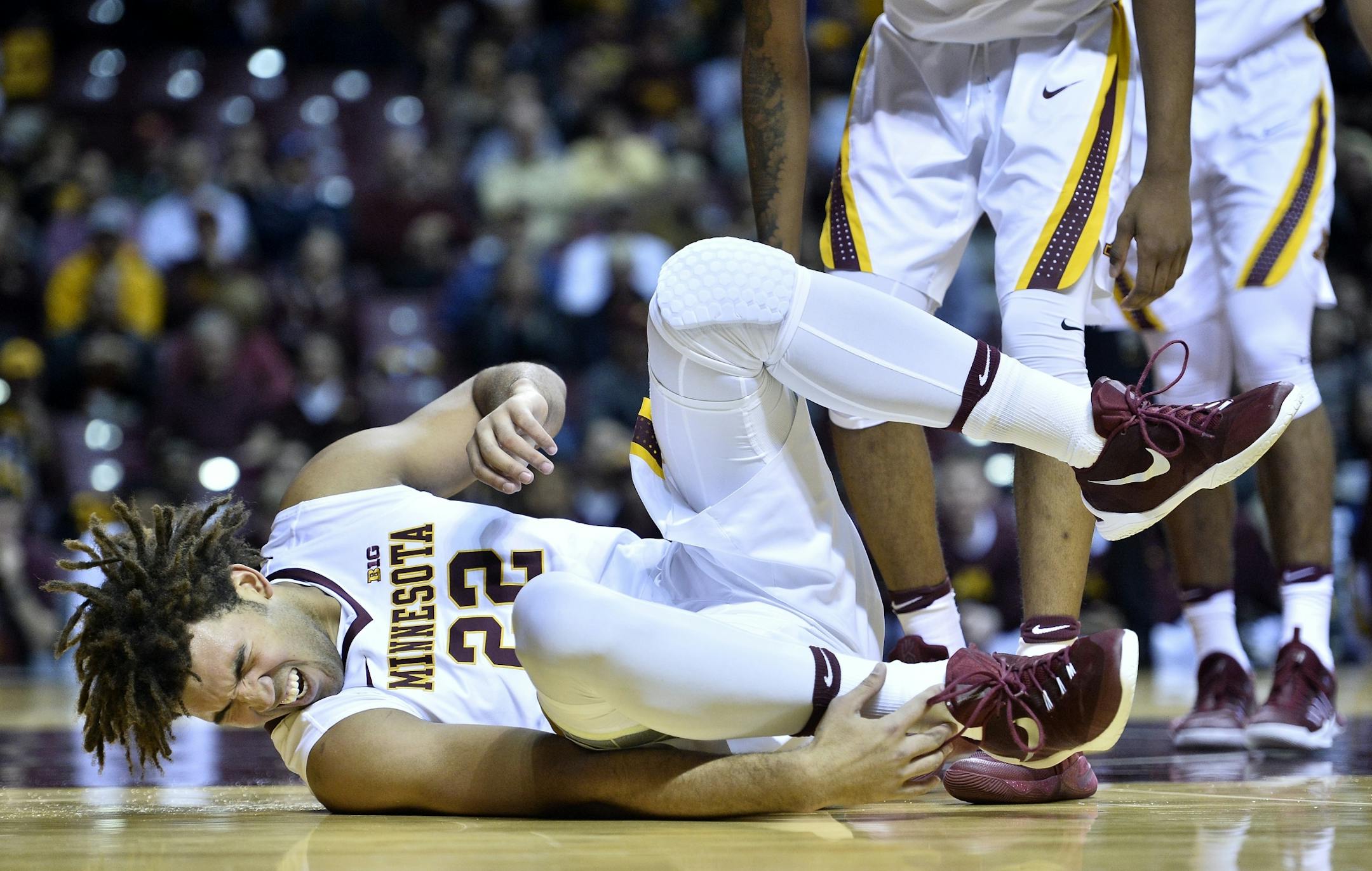 Minnesota Golden Gophers center Reggie Lynch (22) grabbed his ankle in pain after he fell to the floor in the first half against the Arkansas Razorbacks.