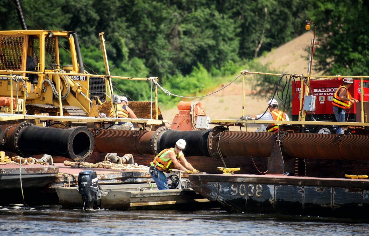 Workers prepare to remove a section of sand transport pipe as the dredge closes in on the edge of the channel. This dredge cuts a 200 foot swath into the navigation channel, insuring a 12-foot deep channel. The sand is dumped on the edge of the channel and will be removed later after safe navigation is restored. Barge and towboat traffic on the Upper Mississippi River is at a standstill after the navigation channel -- through which about half of the nation's grain exports pass -- became clogged