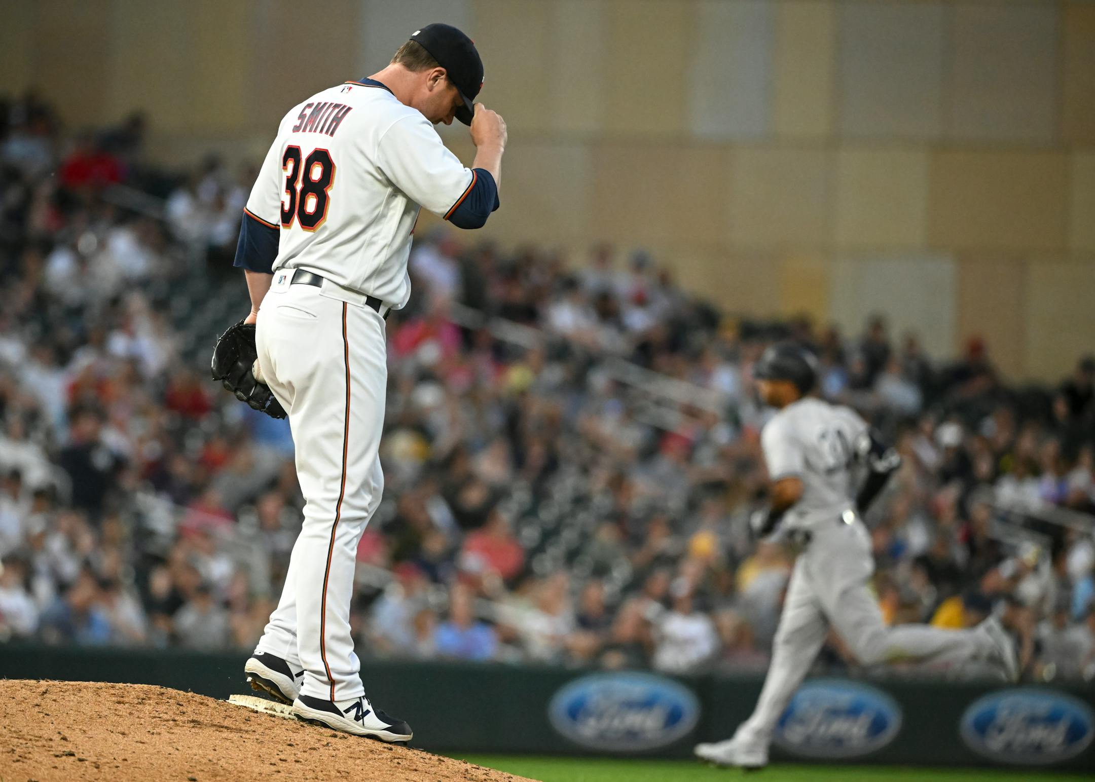 Minnesota Twins relief pitcher Joe Smith (38) adjusts his cap as New York Yankees left fielder Aaron Hicks (31) rounds the bases after Hicks hit a 2-run home run in the top of the sixth inning.