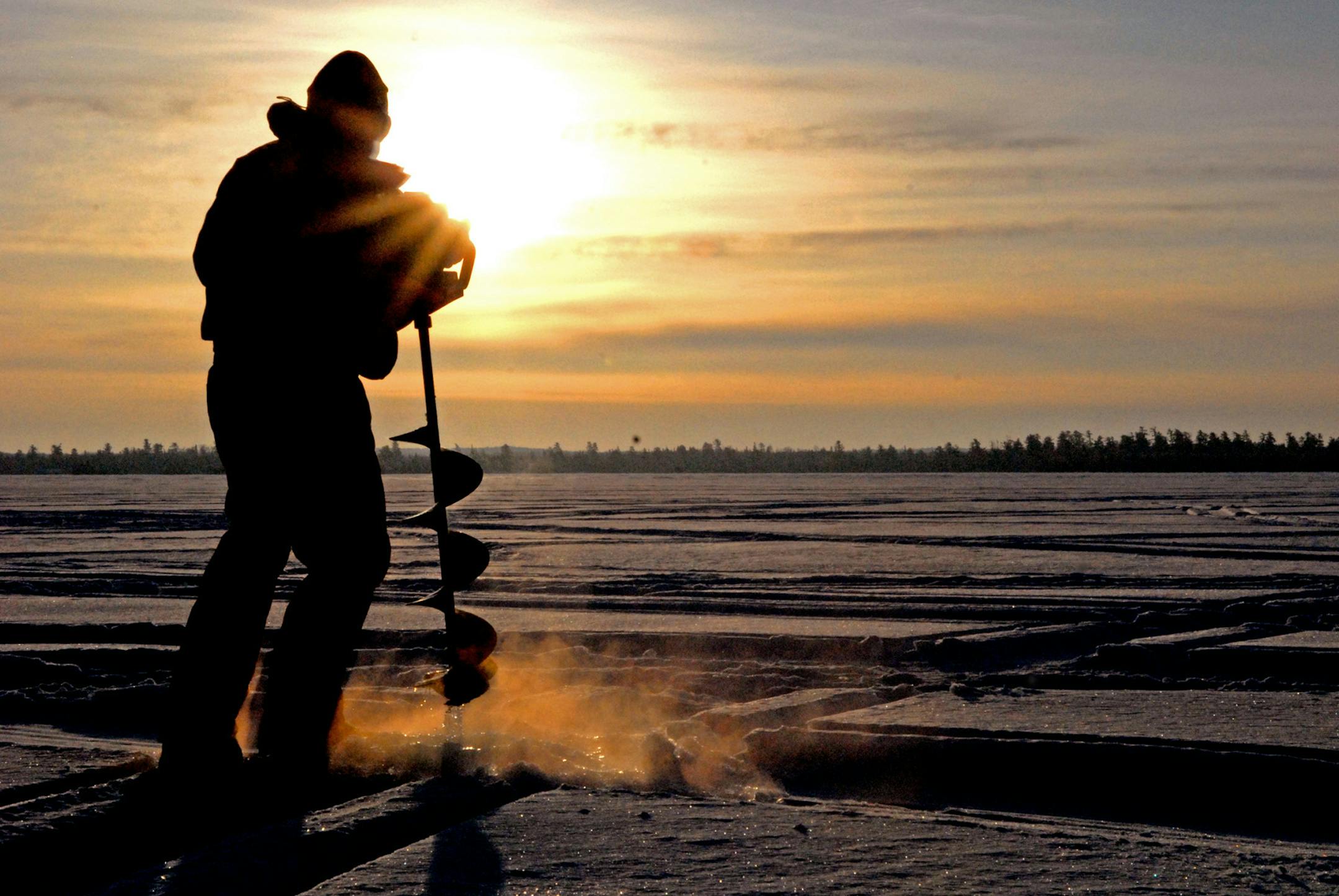 DENNIS ANDERSON ... 1/2009 ... Bill Hanzel augers a hole through the ice of Snowbank Lake, about 18 miles from Ely. Snowbank Lake lies about half inside and half outside the Boundary Waters Canoe Area Wilderness. For the first time in almost 20 years, an ice road has not been plowed for anglers on the lake, due to deep snow and slush.