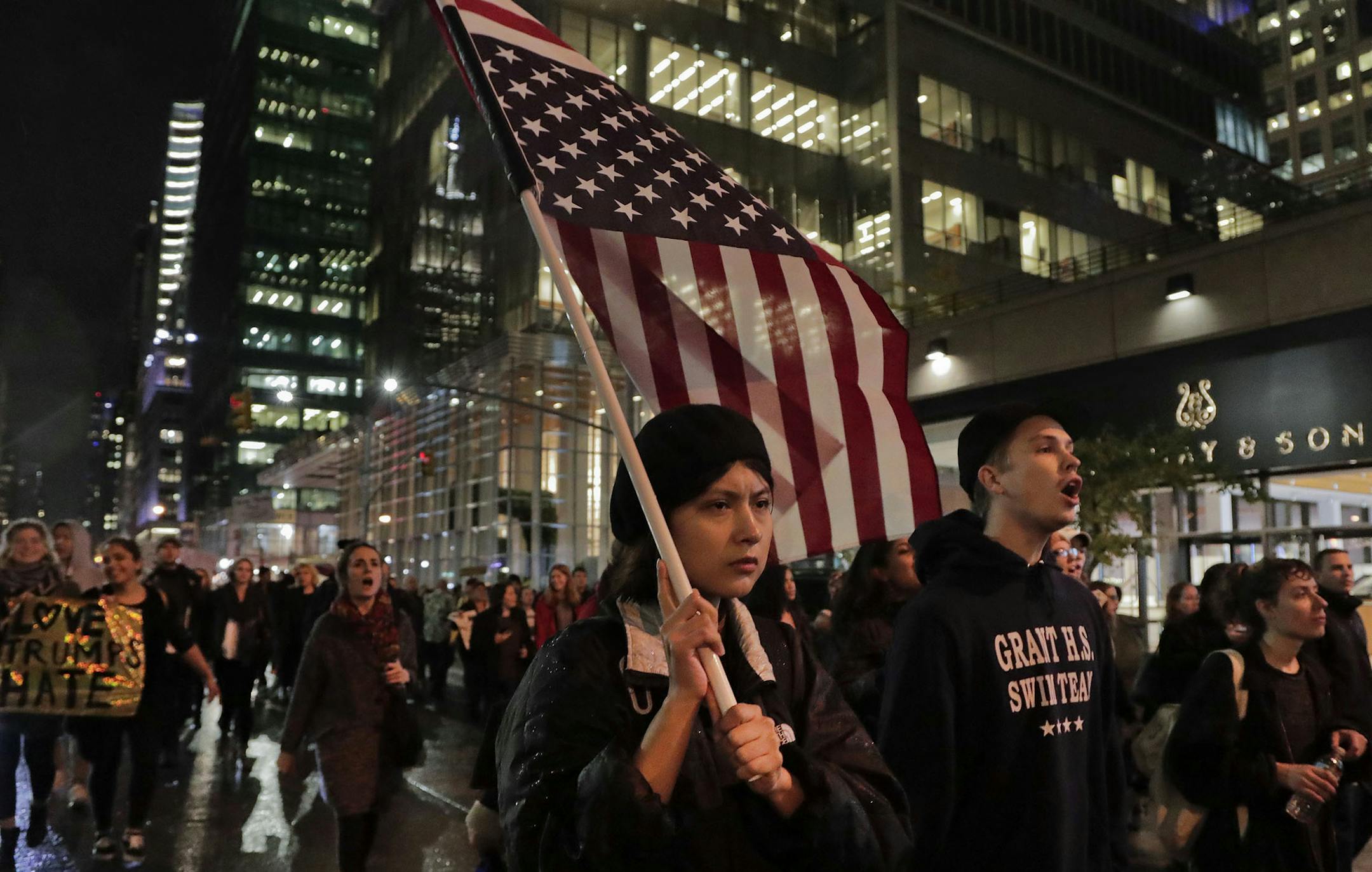 A protester carries an upside down American flag as she walks along Sixth Avenue while demonstrating against President-elect Donald Trump, Wednesday, Nov. 9, 2016, in New York. Thousands of protesters around the country took to the streets Wednesday to condemn the election of Trump as president. (AP Photo/Julie Jacobson) ORG XMIT: MIN2016111012205734
