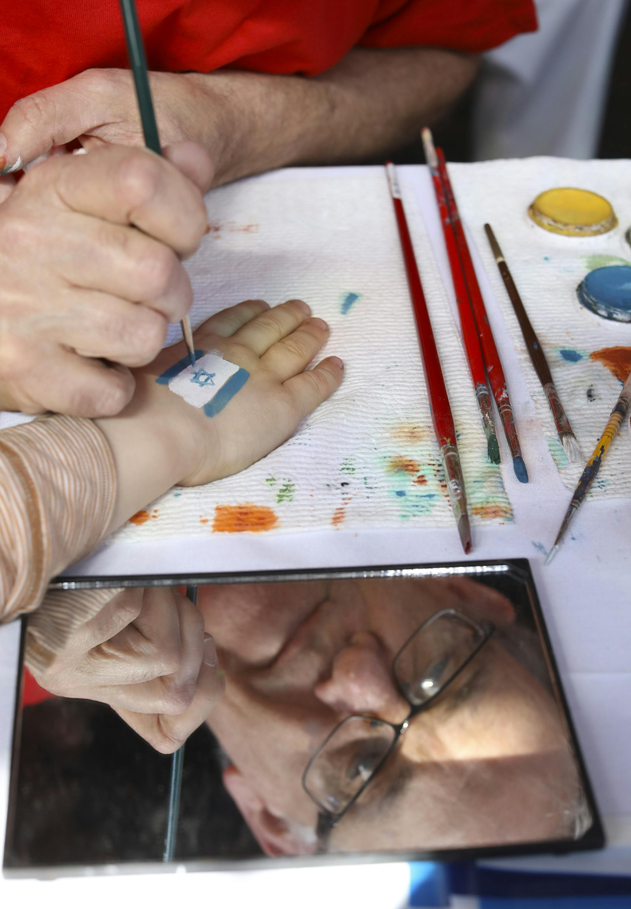 Jim Strohm painted the Israeli flag on the hand of a child during the Israel At 70 celebration Sunday afternoon. ] JEFF WHEELER ï jeff.wheeler@startribune.com A community-wide celebration, Israel At 70, was held Sunday afternoon, April 22, 2018 at the Minneapolis Events Center at St. Anthony Main to celebrate the 70th anniversary of Israel's statehood. Music, food, and dancing for all ages was enjoyed by hundreds of participants.