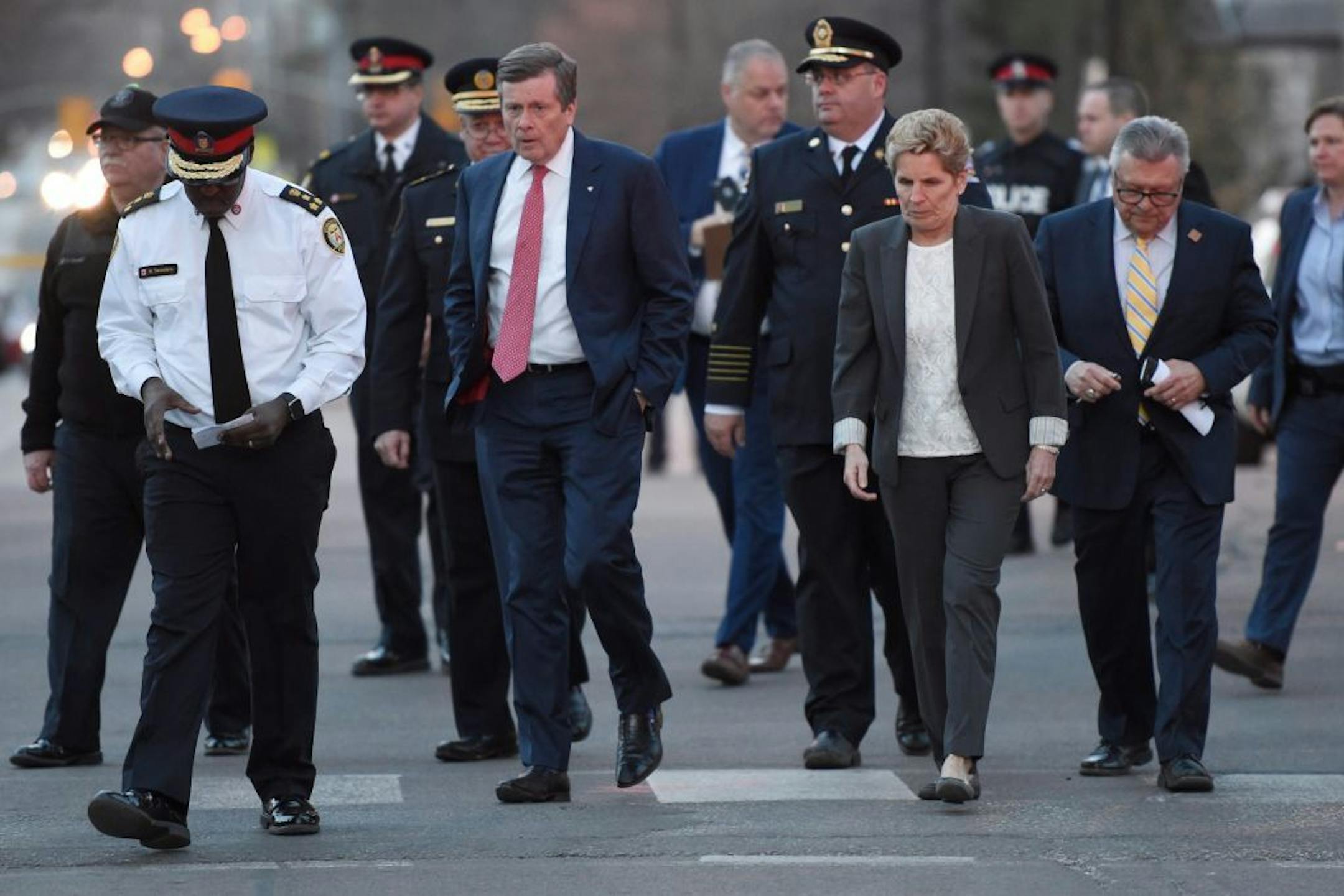 Toronto Police Chief Mark Saunders, front left, Toronto Mayor John Tory, Premier Wynne and Ralph Goodale, Federal Minister of Public Safety and Emergency Preparedness walk together towards a news conference after viewing the scene where a rented van plowed down a crowded Toronto sidewalk on Monday, April 23, 2018. The driver fled and was quickly arrested in a confrontation with police, Canadian authorities said.