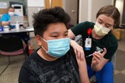 Kuabcag Yang, 13, of Brooklyn Park, Minn. got his first dose of the Pfizer COVID-19 vaccine from nurse Jenn Doble Thursday at Children's Minnesota. ] 