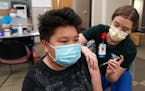 Kuabcag Yang, 13, of Brooklyn Park, Minn. got his first dose of the Pfizer COVID-19 vaccine from nurse Jenn Doble Thursday at Children's Minnesota. ] 