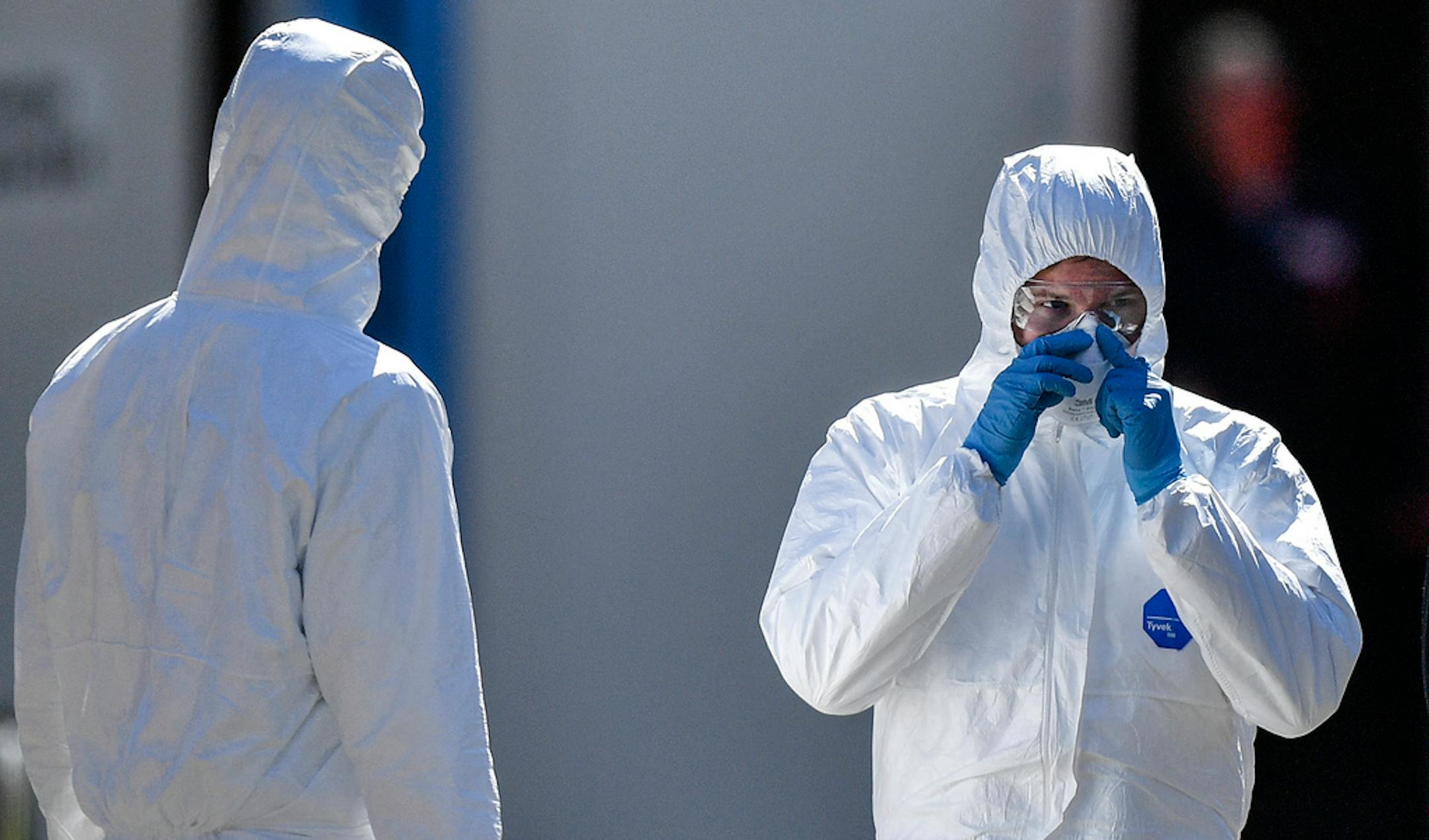 Employees wearing protective clothings wait in the warm sun for the next patient at a coronavirus test station outside the hospital 'Klinikum Nord' in Dortmund, Germany, Saturday, April 4, 2020.