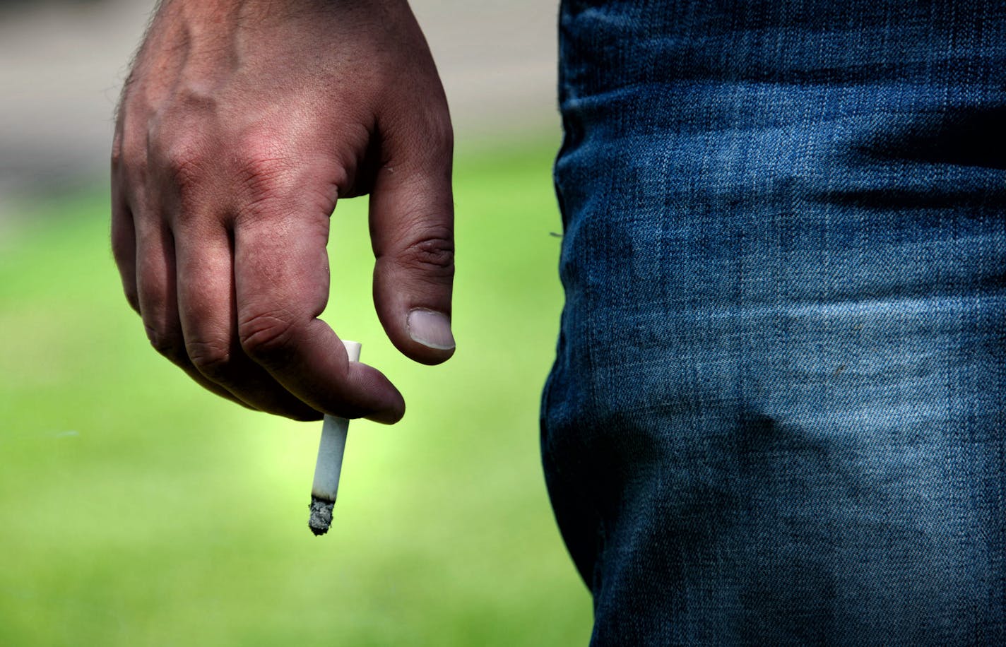 This man was smoking on the curb between Lake St next to Lake Calhoun North Beach as a courtesy to other people at the park. Smoking is already not allowed at the beaches of Lake Calhoun Park. The Minneapolis Park Board Recreation Committee is proposing to ban smoking in all city parks. Wednesday, June 4, 2014 ] GLEN STUBBE * gstubbe@startribune.com