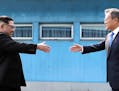 North Korean leader Kim Jong Un, left, prepares to shake hands with South Korean President Moon Jae-in over the military demarcation line at the borde