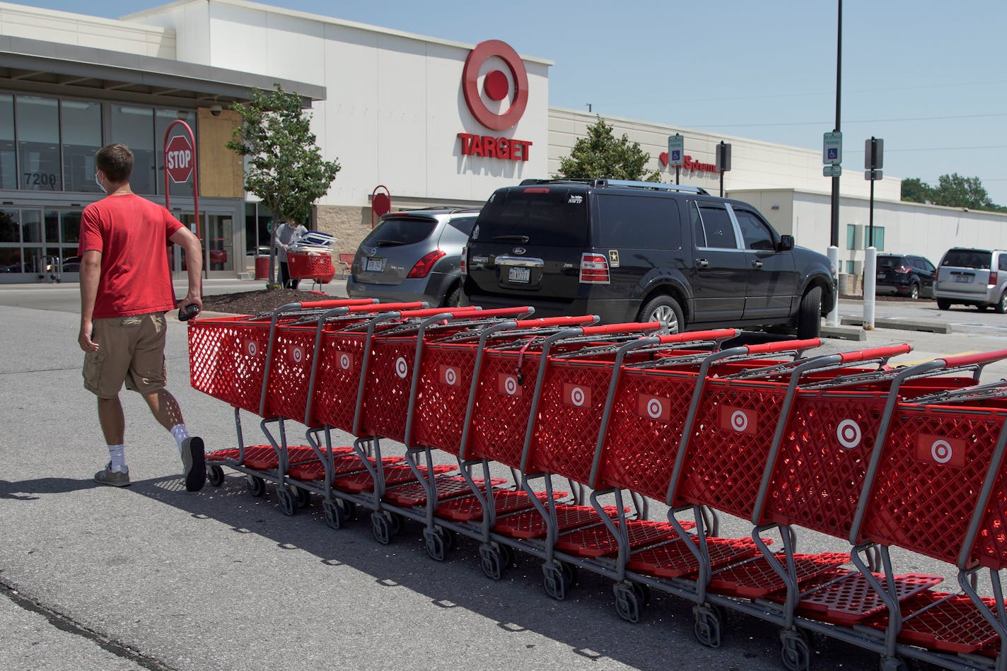 FILE - A Target employee returns shopping carts from the parking lot, in Omaha, Neb., Tuesday, June 16, 2020. Target Corp. says it's permanently increasing starting hourly wages for its workers to $15 beginning July 5, several months ahead of schedule. (AP Photo/Nati Harnik)