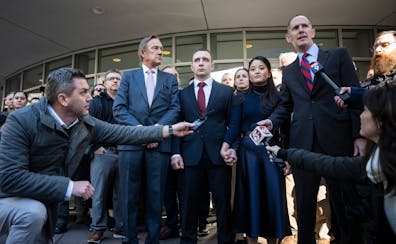 Trooper Ryan Londregan, center stood hand-in-hand with his wife surrounded by security, his lawyers and dozens of supporters after his first court app