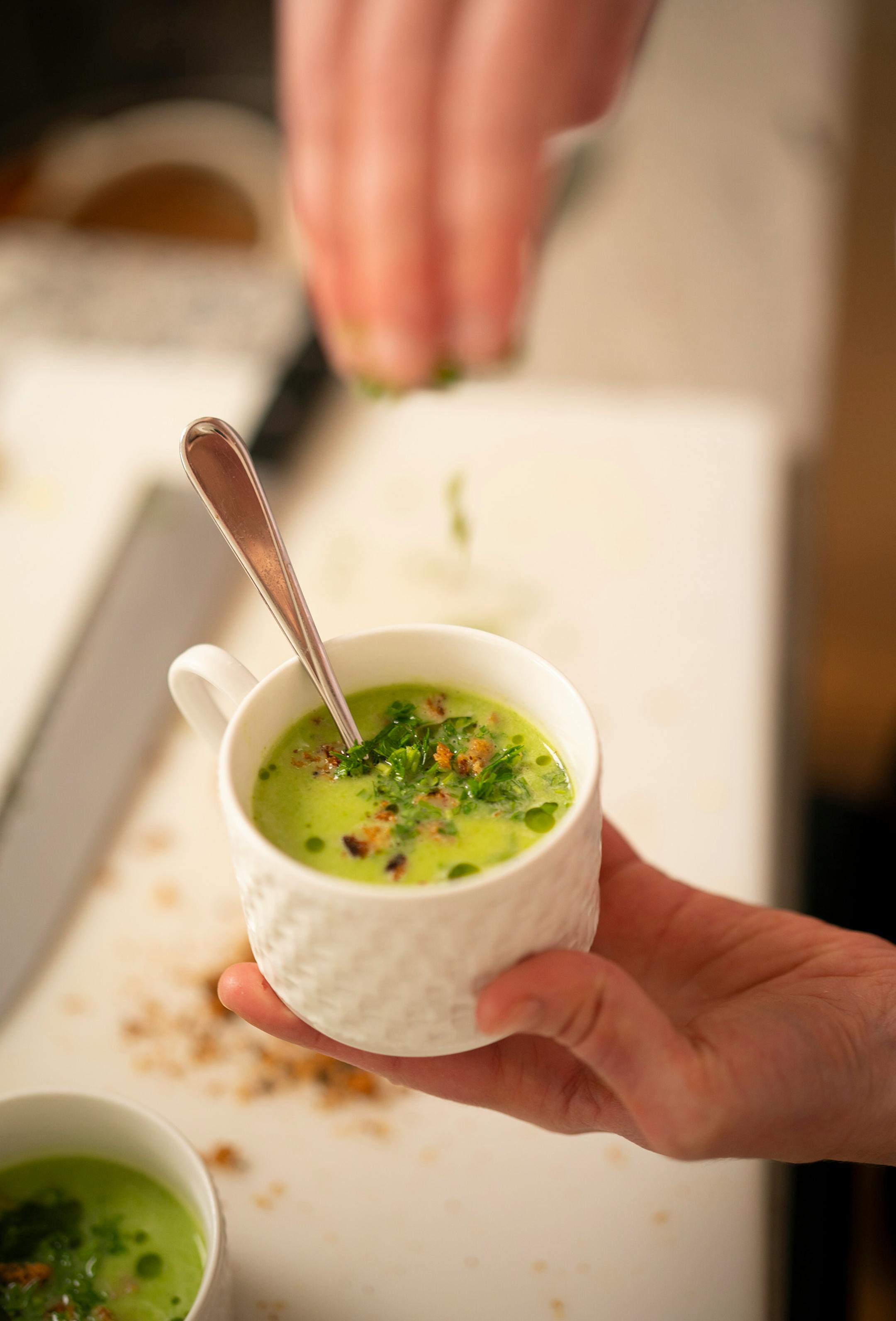 Chef Karyn Tomlinson added a some cilantro while garnishing a cup of the asparagus leek soup she demonstrated how to make for her Instagram show. Since the pandemic began, former Corner Table chef Karyn Tomlinson has been a prolific poster to Instagram, offering free cooking lessons with her show "Karyn's Quarantine Kitchen." She was photographed producing a segment on preparing pureed soups Thursday afternoon, April 23, 2020 in the kitchen of her condo.