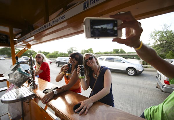 Gina Chov and Kate Curtis, right, posed for a commemorative photo as they crossed the Hennepin Ave. bridge on a Pedal Pub with a group of co-workers T