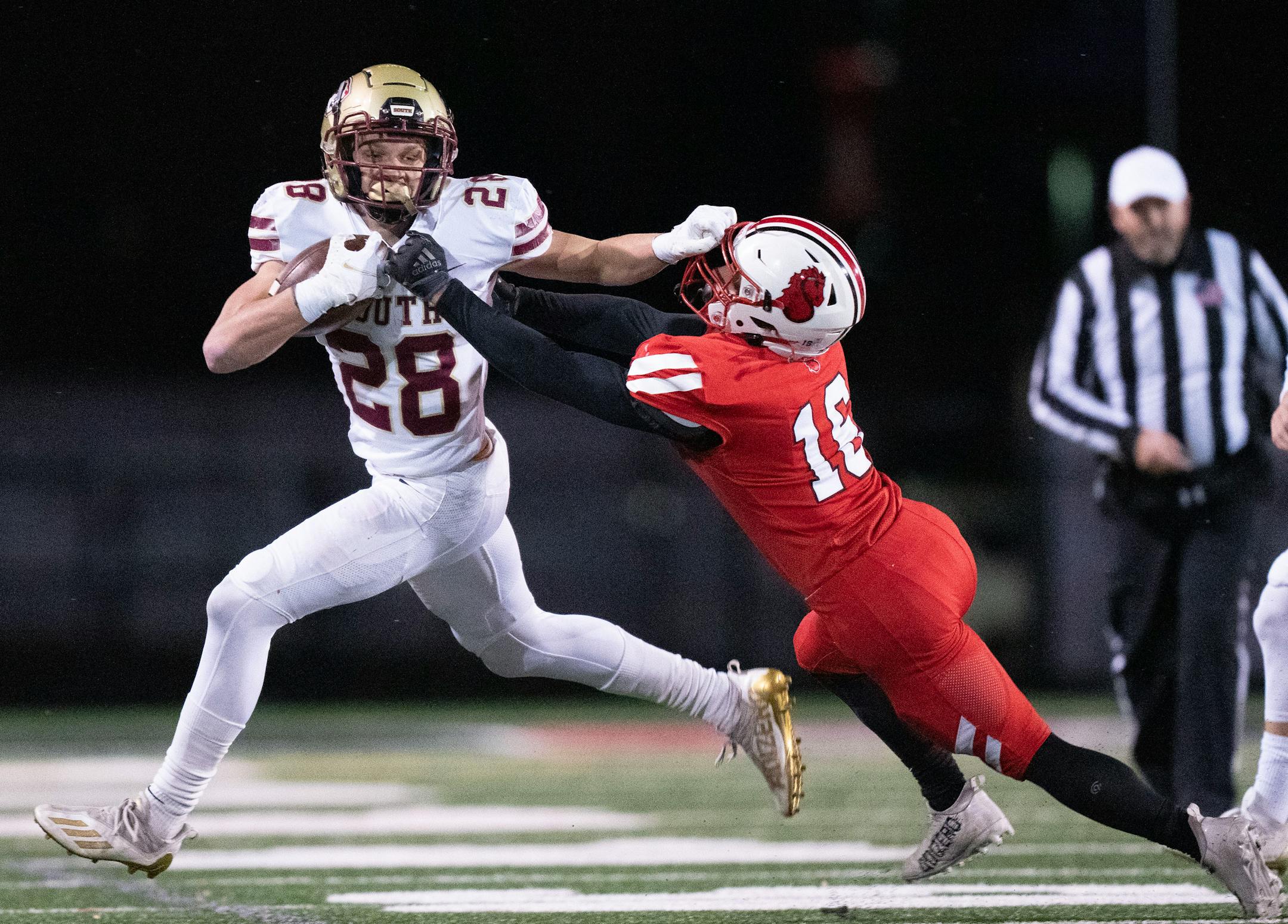 Lakeville South running back Carson Hansen (28) stiff arms Stillwater defensive back Braden Wenner (16) in the second quarter of a Class 6A quarterfinal game against Stillwater Friday, Nov. 11, 2022 at Eden Prairie High School in Eden Prairie, Minn. ]