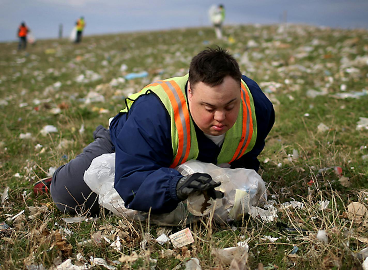 Scott Rhude, 33, sits spread-eagled in a field of garbage, reaching for a piece of trash while on a work assignment with a sheltered workshop "enclave" Tuesday, April 28, 2015, near the landfill in Wilmar, MN. Like many of his coworkers on the cleanup crew, Rhude dreams of landing a ìreal jobî in the community. But for that, he would need specialized training, transportation to and from work and access to a job coach.ìHe is stuck, stuck stuck,î said Mary Rhude, Scottís mother.](DAVID JOLES/START