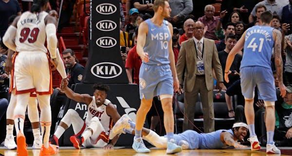 The Timberwolves' D'Angelo Russell, bottom right, reacts as the Heat's Jimmy Butler shows frustration after they both went down in the fourth quarter 