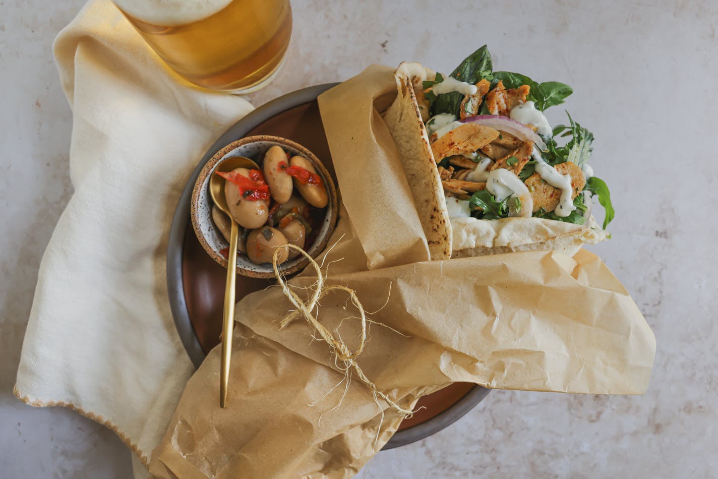 A plate with a chicken gyro drizzled with Tzatziki and served with marinated olives.