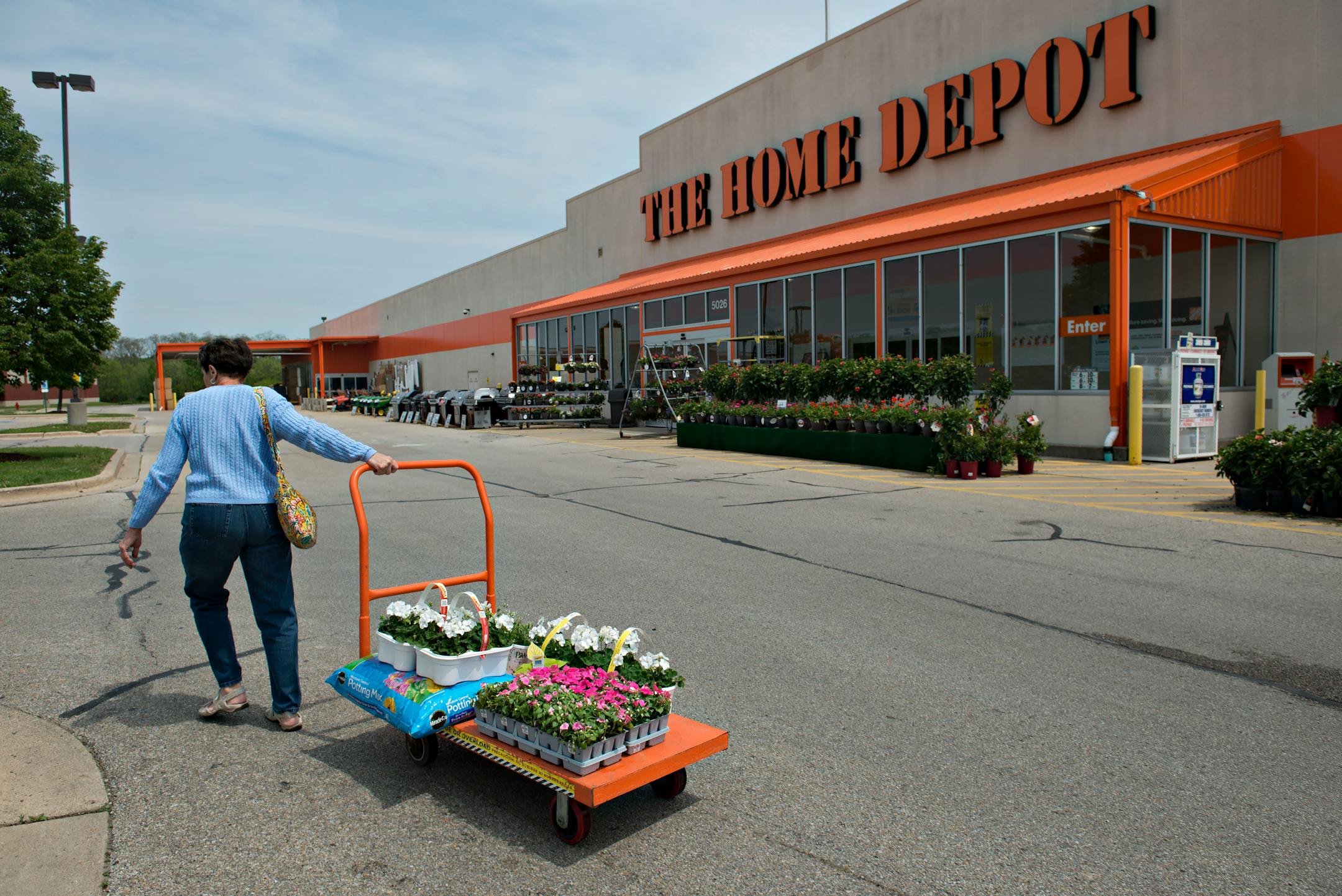 Margo Schroeder pulls a cart of flowers outside a Home Depot Inc. store in Peoria, Illinois, U.S., on Monday, May 19, 2014. Home Depot Inc., the largest U.S. home-improvement retailer, posted first-quarter profit that trailed some analysts� estimates after a long winter slowed the rebound in the housing market. Photographer: Daniel Acker/Bloomberg *** Local Caption *** Margo Schroeder