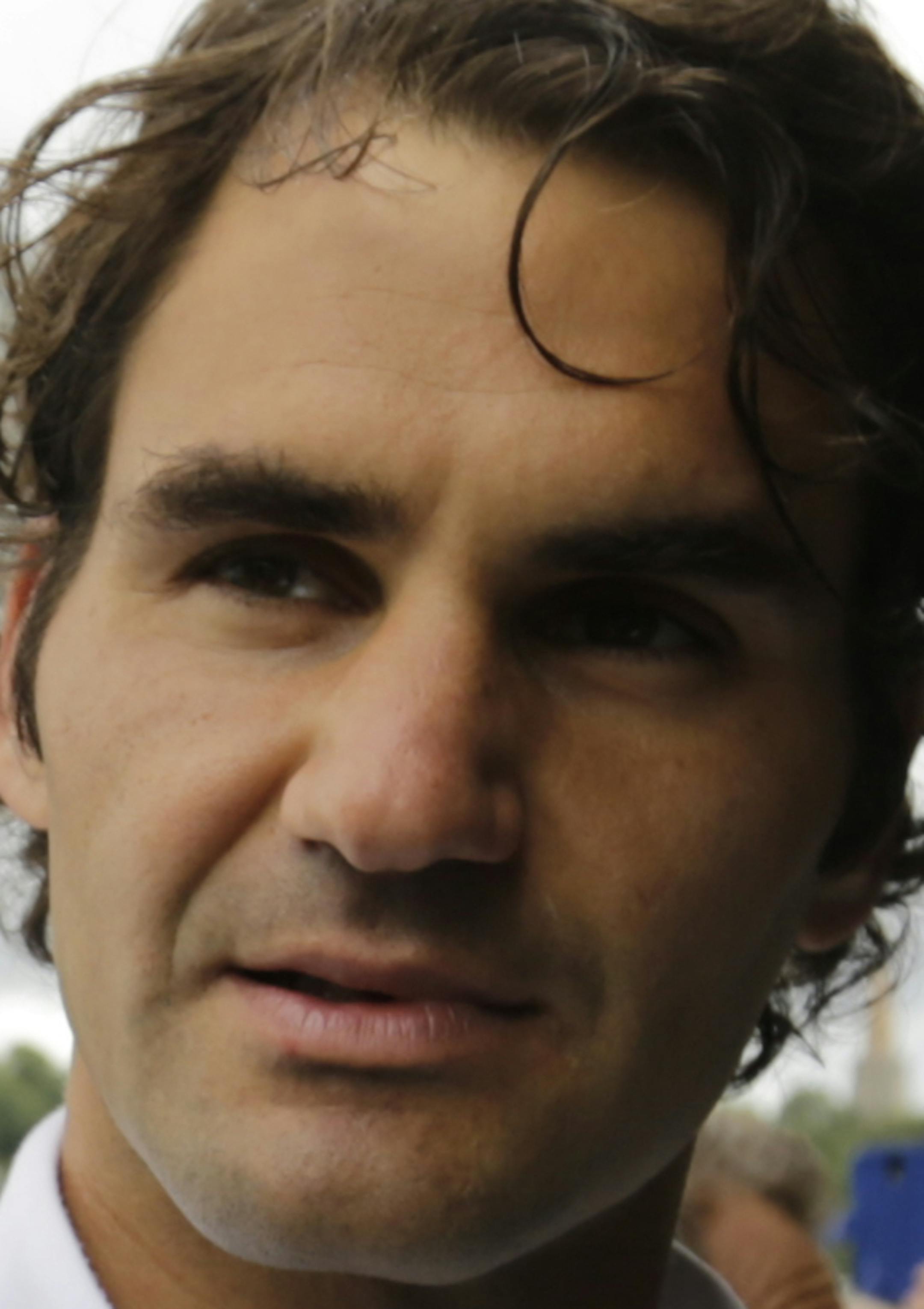 Roger Federer of Switzerland signs autographs as he returns from a practice session at the All England Lawn Tennis Championships at Wimbledon, London, Saturday July 5, 2014. (AP Photo/Ben Curtis)