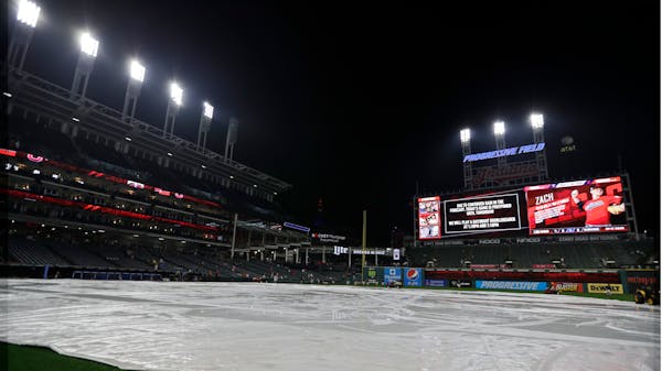 The tarp rests on the field after a game between the Twins and Indians was postponed due to the weather on Friday