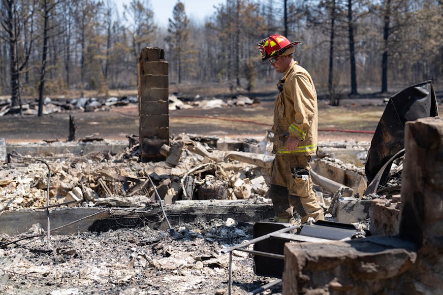Jon Settergren, a Nisswa firefighter, surveys the smoldered remains of a structure as part of the efforts to combat the Camp House wildfire in Brimson, Minn. on Thursday, May 15, 2025.   ]

ALEX KORMANN • alex.kormann@startribune.com