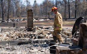 Jon Settergren, a Nisswa firefighter, surveys the smoldered remains of a structure as part of the efforts to combat the Camp House wildfire in Brimson