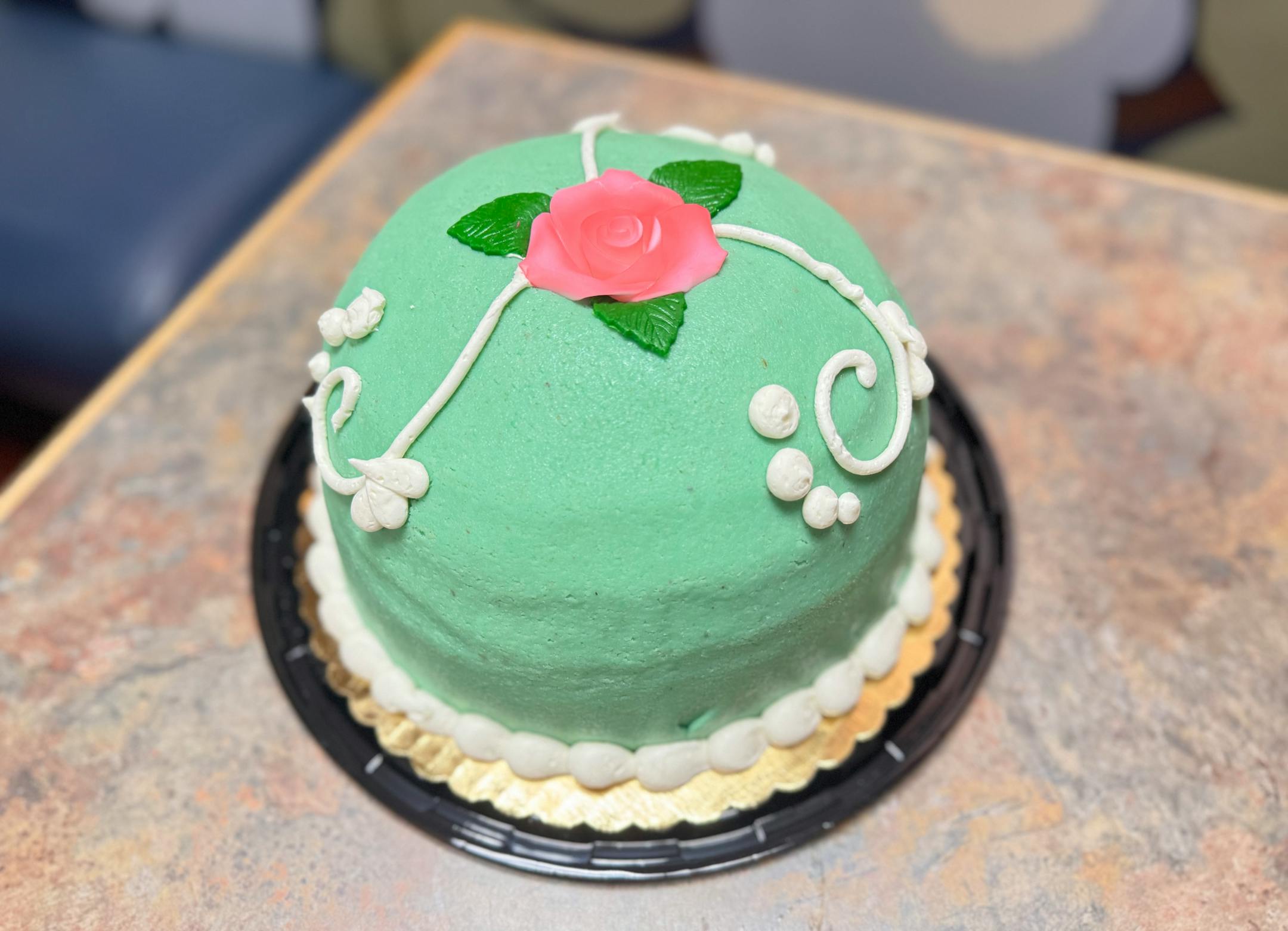 Taste of Scandinavia's Princess Torte sponge cake wrapped in green marzipan and garnished with a rose.