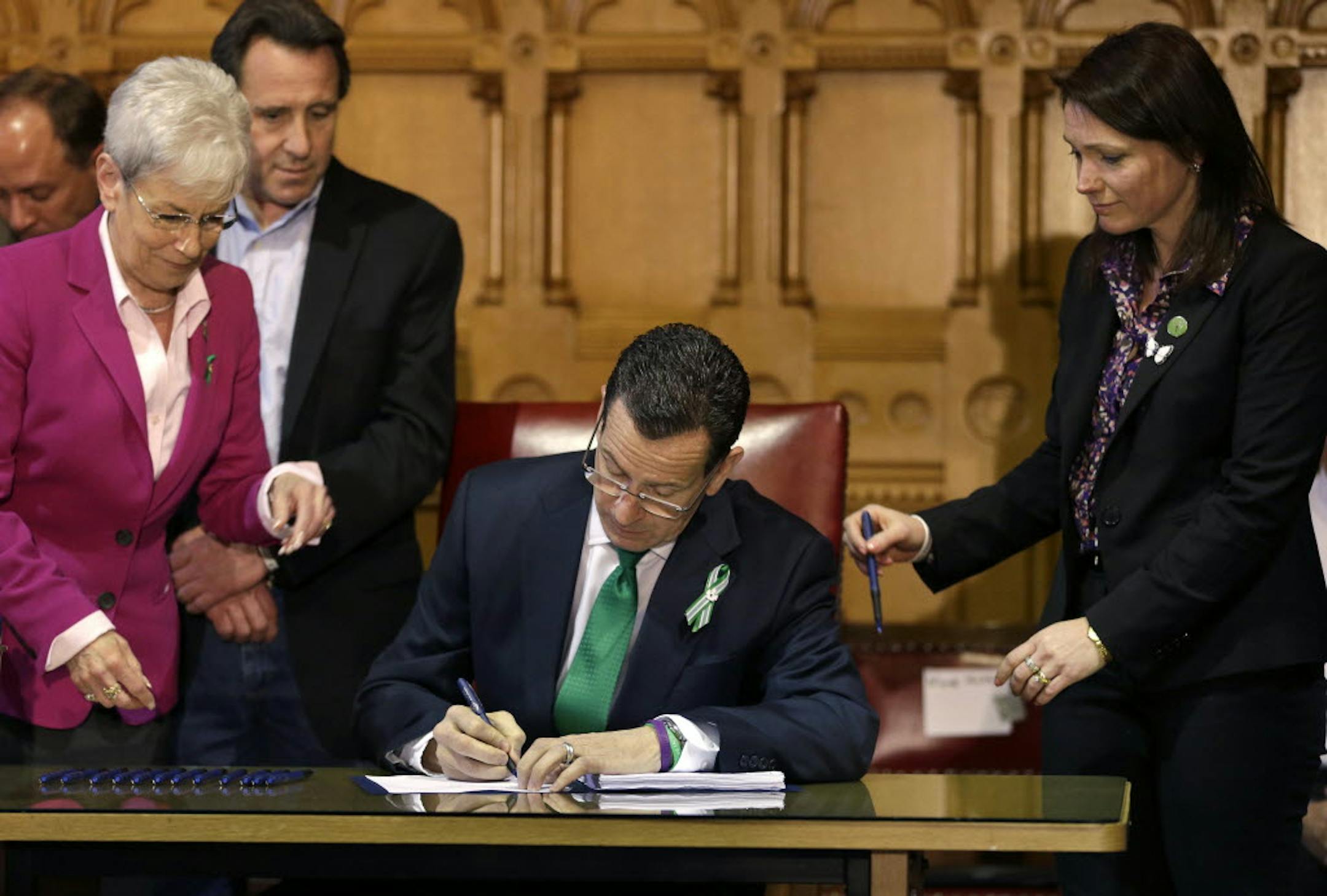 Connecticut Gov. Dannel P. Malloy, center, signs legislation at the Capitol in Hartford, Conn., Thursday, that includes new restrictions on weapons and large capacity ammunition magazines.