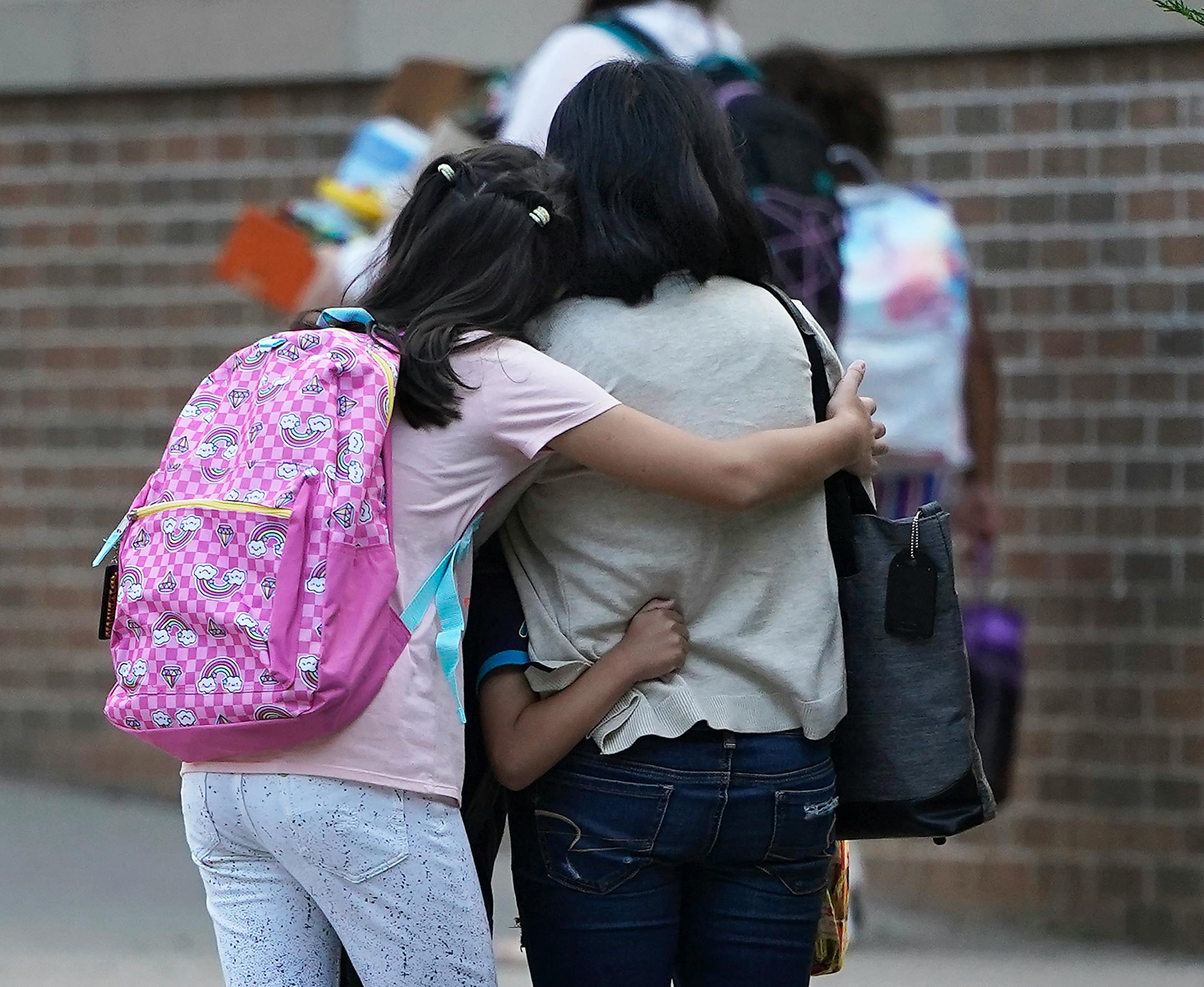 Mother Digna (Adonis )Nichols, who works as an educator at Anishinabe Academy got a hug from her children Zayna, 9, a 4th grader and Arlo, 6, a 1st grader who attend Sullivan STEAM School, housed in the same building as Anishinabe, on the first day of school   Tuesday in Minneapolis.