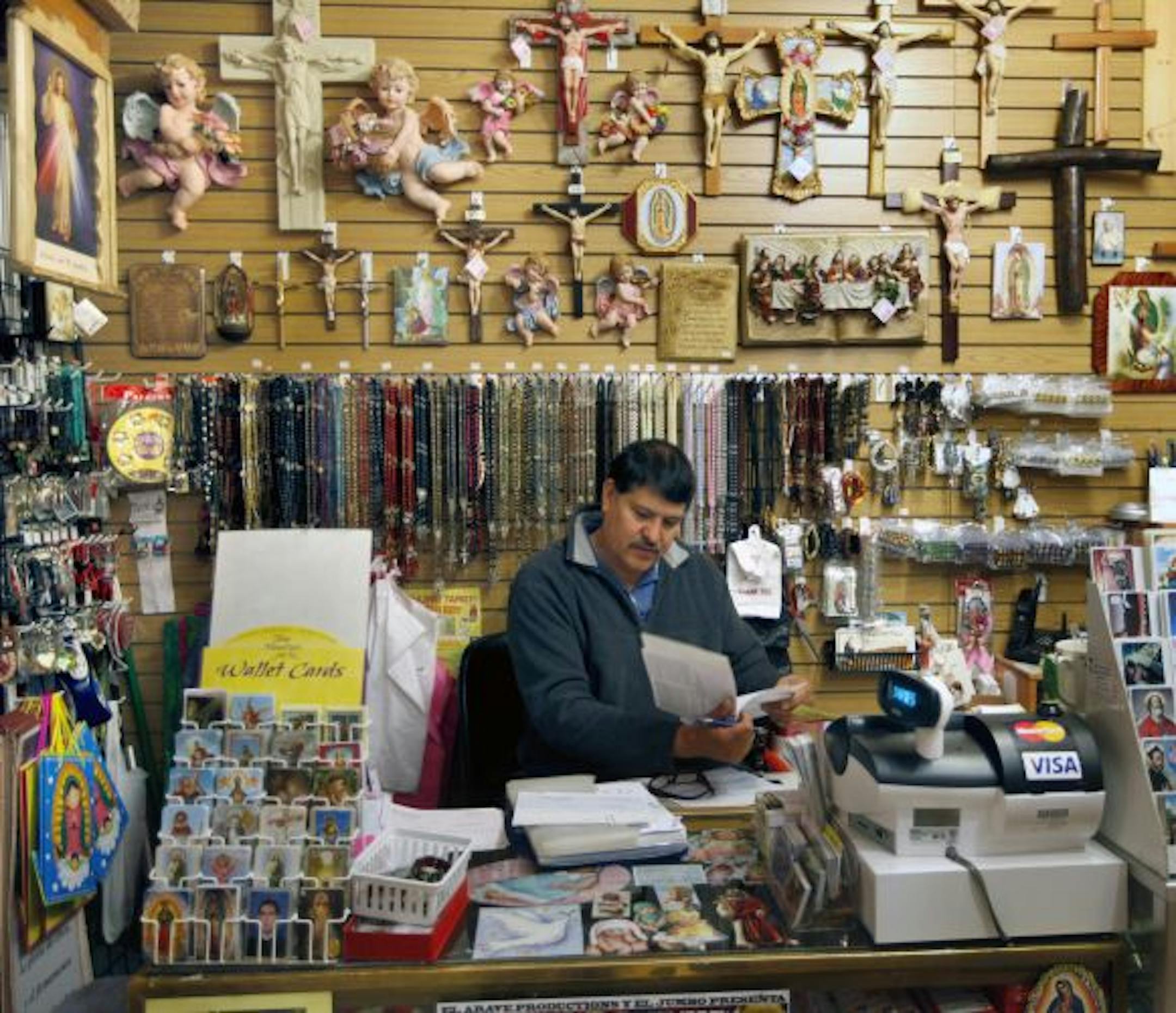Victor Carta does a little paperwork behind the counter at Librería LaPaz, in Mercado Central on Lake Street in Minneapolis.
