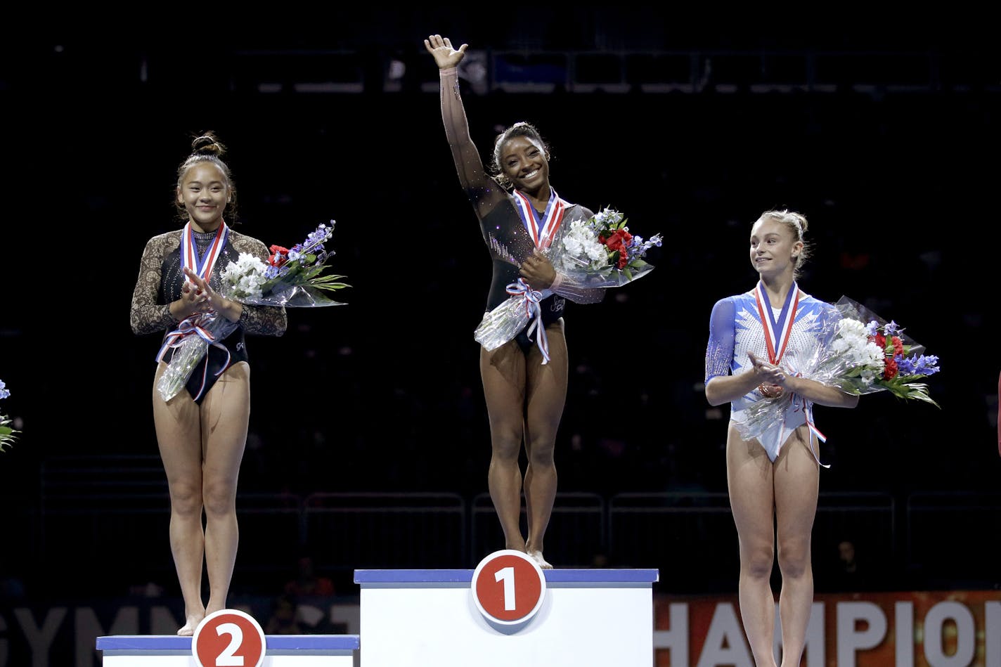 All-around winner Simone Biles, center, stands on the podium with second place finisher Sunisa Lee, left, and third place finisher Grace McCallum after the senior women's competition at the 2019 U.S. Gymnastics Championships Sunday, Aug. 11, 2019, in Kansas City, Mo. (AP Photo/Charlie Riedel) ORG XMIT: MOCR120