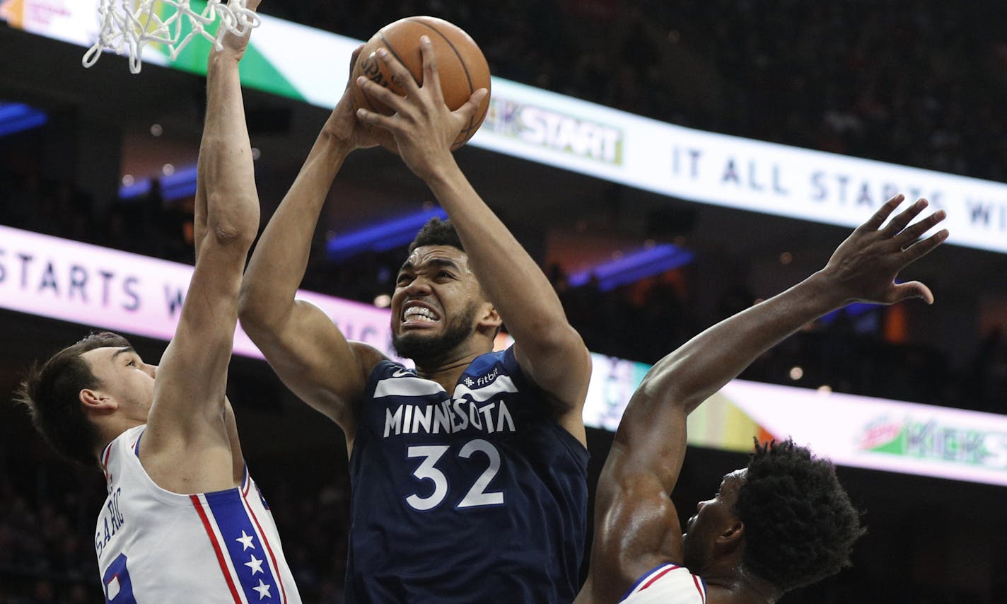 Minnesota Timberwolves' Karl-Anthony Towns, center, goes up for a shot between Philadelphia 76ers' Dario Saric, left, and Joel Embiid, right, during the first half of an NBA basketball game Saturday, March 24, 2018, in Philadelphia. (AP Photo/Chris Szagola)