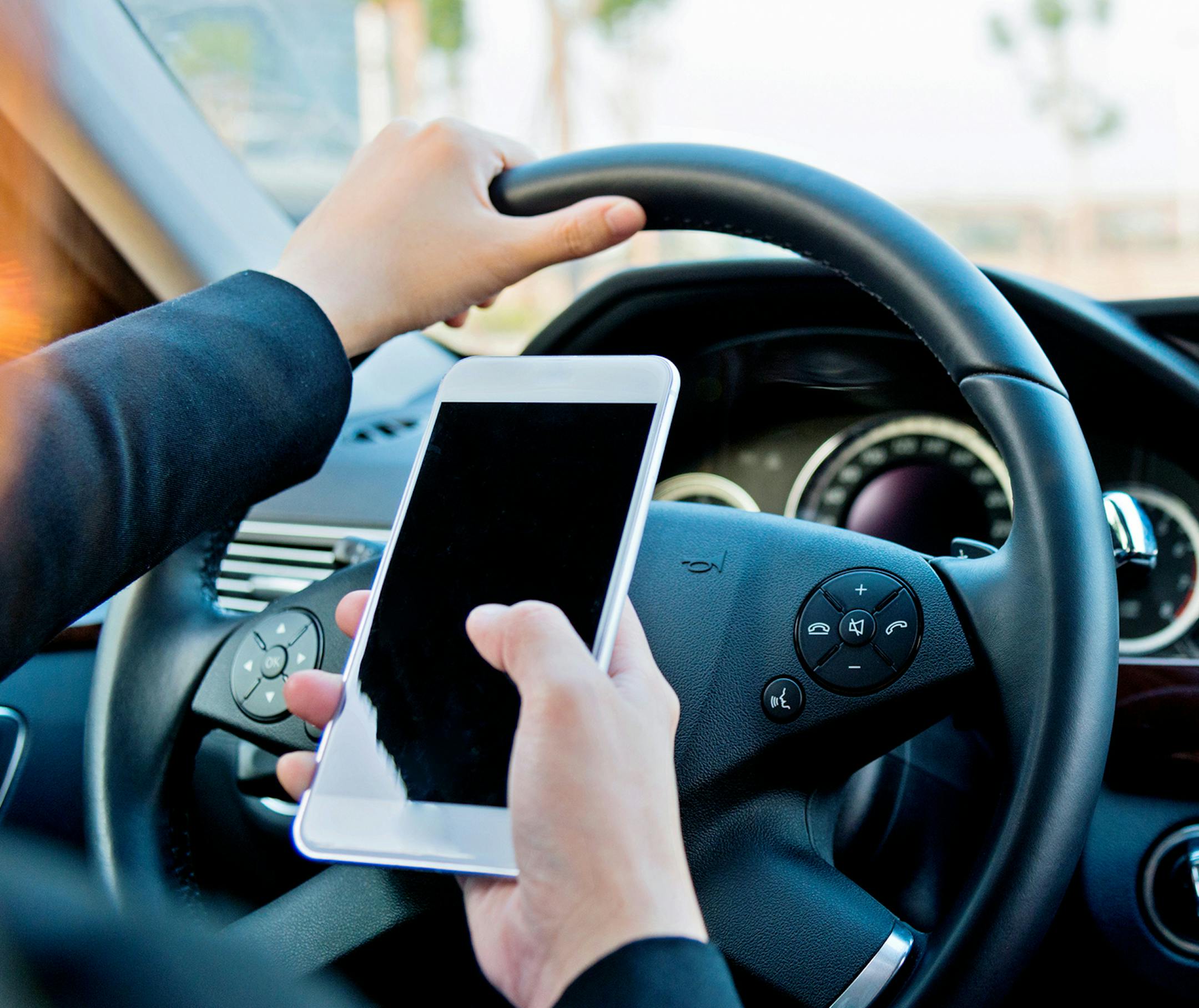 Female driver texting on mobile phone while driving.