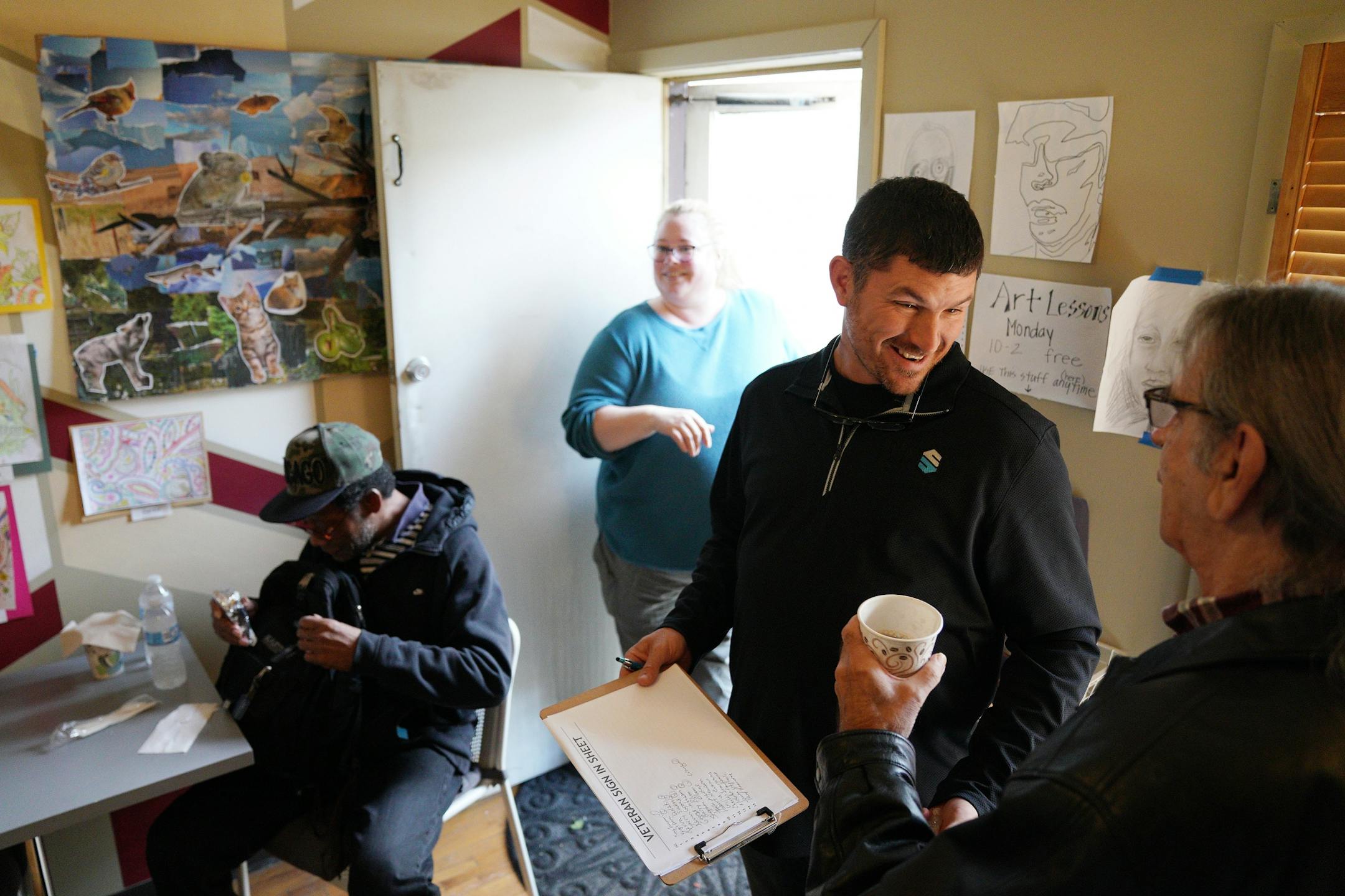 Tom McKenna, center, talked with a veteran as he compiled a list for them to go shopping for free supplies at his attached donation center.