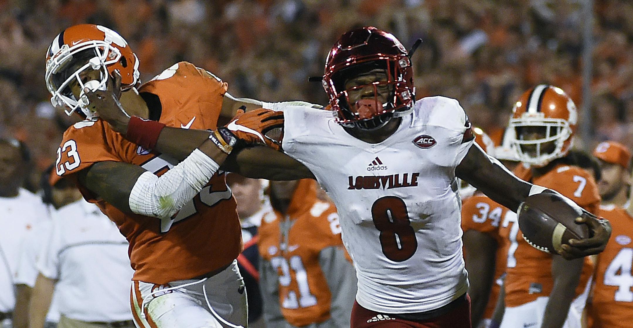 FILE - In this Oct. 1, 2016, file photo, Louisville quarterback Lamar Jackson (8) stiff-arms Clemson safety Van Smith (23) as he goes out of bounds during the second half of an NCAA college football game, in Clemson, S.C. The AP college football Player of the Year will be announced Tuesday, Dec. 13, 2016. Jonathan Allen, of Alabama, Lamar Jackson, of Louisville, and Deshaun Watson, of Clemson, are the top three vote-getters. (AP Photo/Rainier Ehrhardt, File)