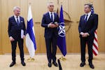 NATO Secretary General Jens Stoltenberg, center, speaks as Finland's Foreign Minister Pekka Haavisto, left, prepares to hand over a document to United