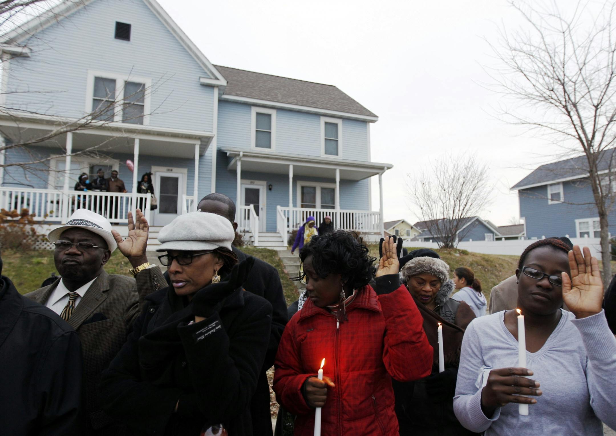 Family and friends pray during a vigil for murder victims Beatrice Wilson and her grandson Peter Wilson outside the house, back left, where the crime took place, in Minneapolis, Sunday, Nov. 4, 2012. Both victims were allegedly killed by Ishmael Roberts, Beatrice Wilson's son, with a Samurai sword. (Genevieve Ross/Special to the Star Tribune) ORG XMIT: 4VIGIL1105