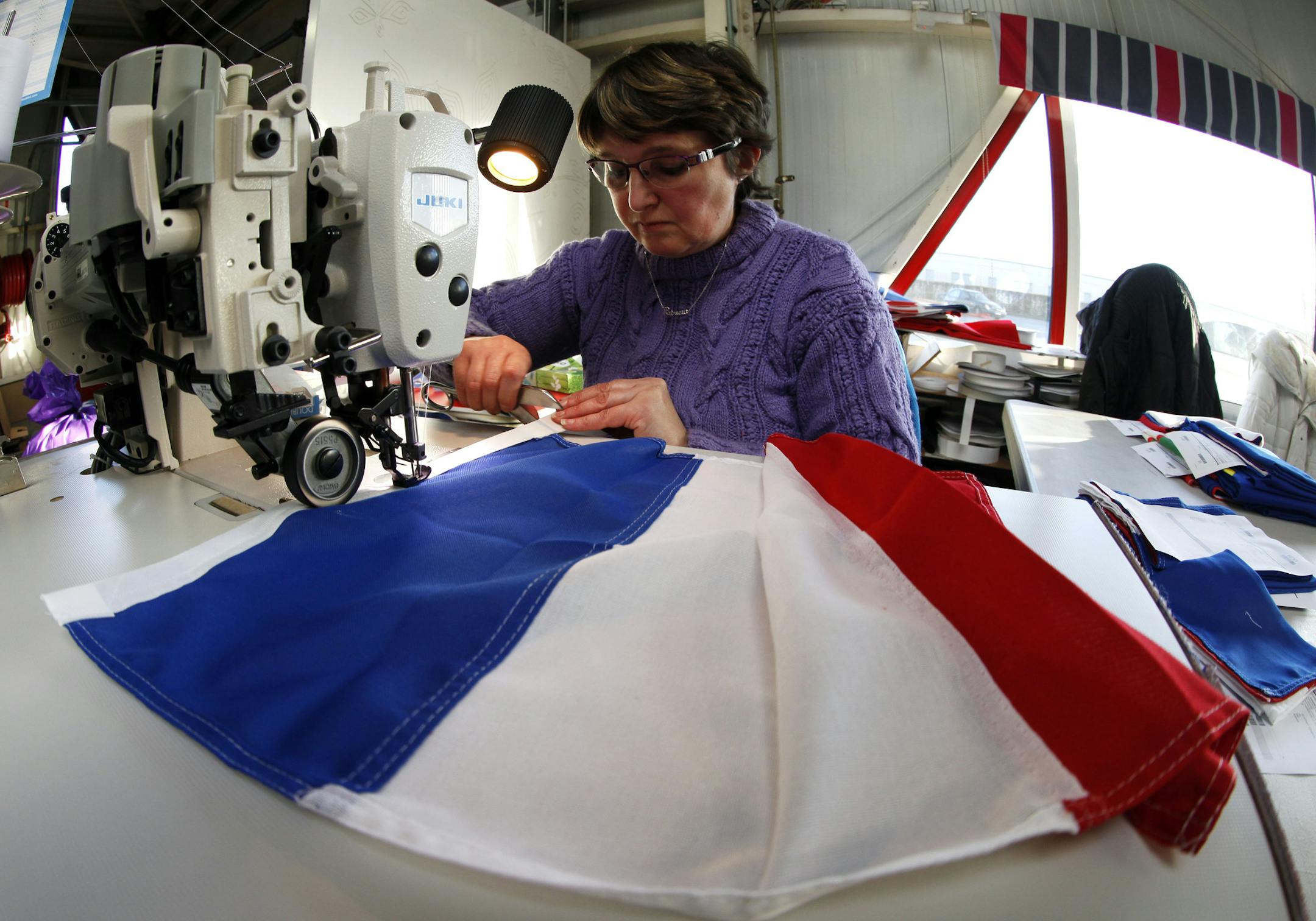 Patricia Toillon, 50, works on a French flag at the Doublet factory, which specializes in making the national flag, in Avelin, near Lille, northern France, Thursday, Nov. 26, 2015. Flying the French flag in a garden — for decades considered bad taste or a symbol of ultranationalism — is now back in favor with the French after the deadly attacks on Paris. (AP Photo/Michel Spingler)