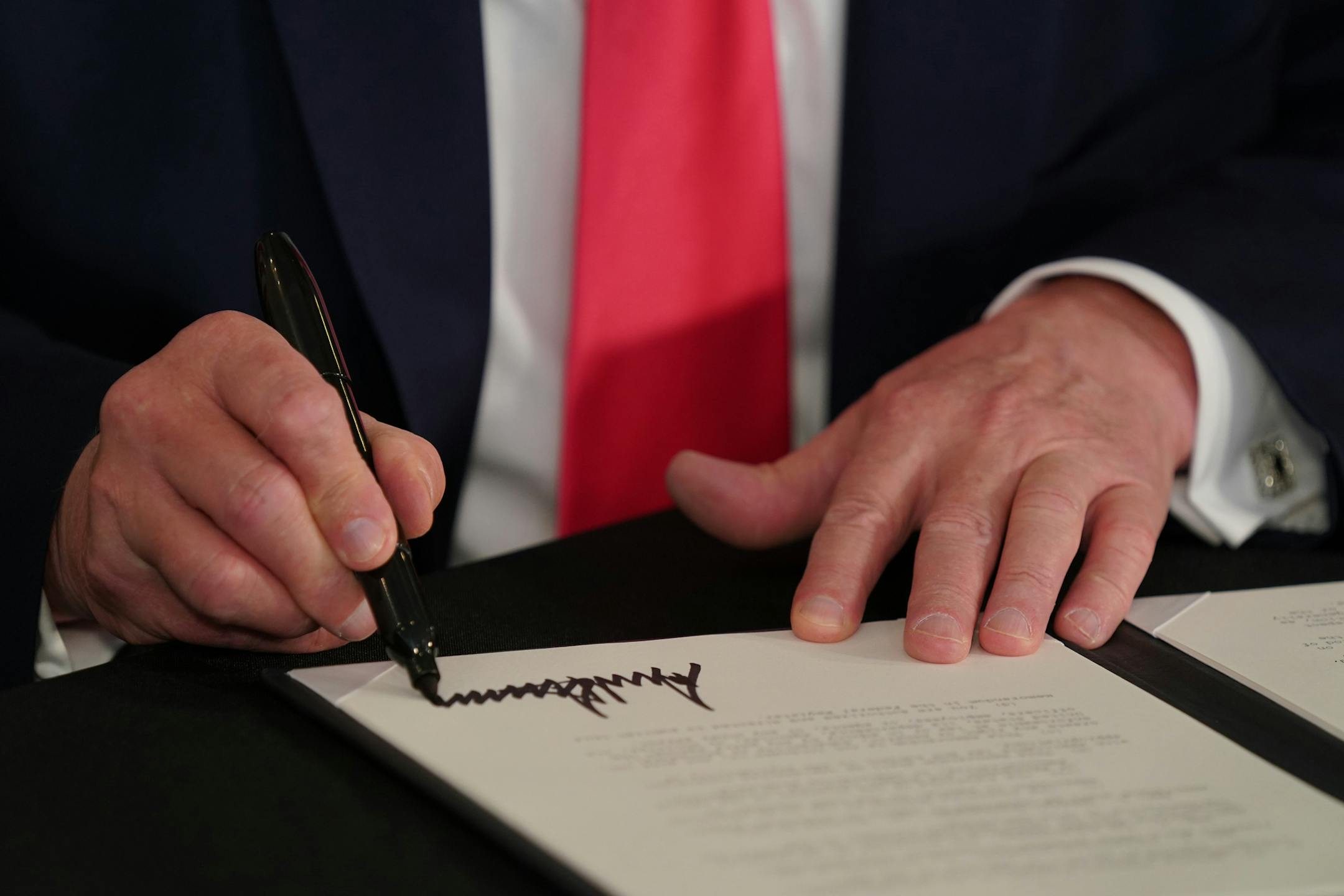 President Donald Trump signs an executive order related to coronavirus pandemic relief during a news conference at Trump National Golf Club in Bedminster, N.J., on Aug. 8, 2020. (Anna Moneymaker/The New York Times)