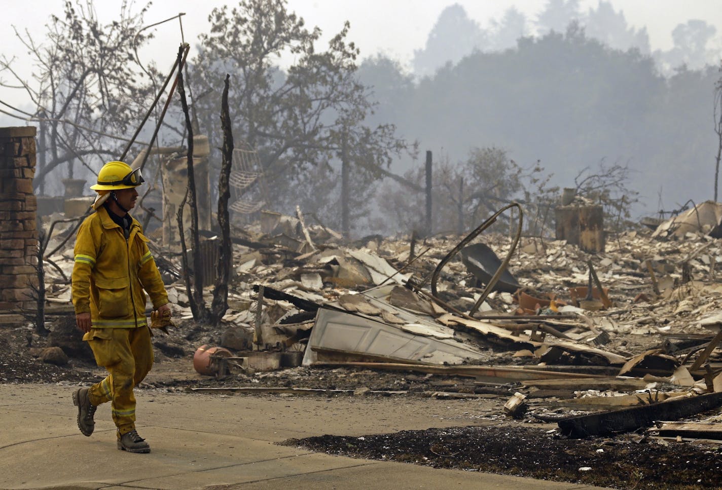 A fireman looks for hotspots in the Fountaingrove area of Santa Rosa, where Medtronic had to evacuate one of its facilities on Monday. (AP Photo/Ben Margot)